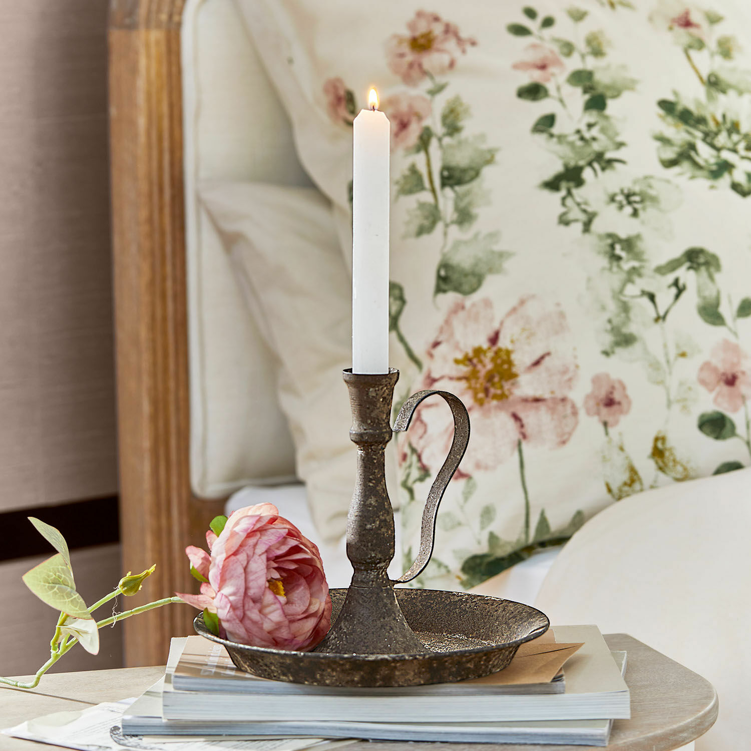 Bougeoir Plixora Chandelier en métal rustique avec bougie blanche et fleur rose posé sur une pile de livres décoratifs