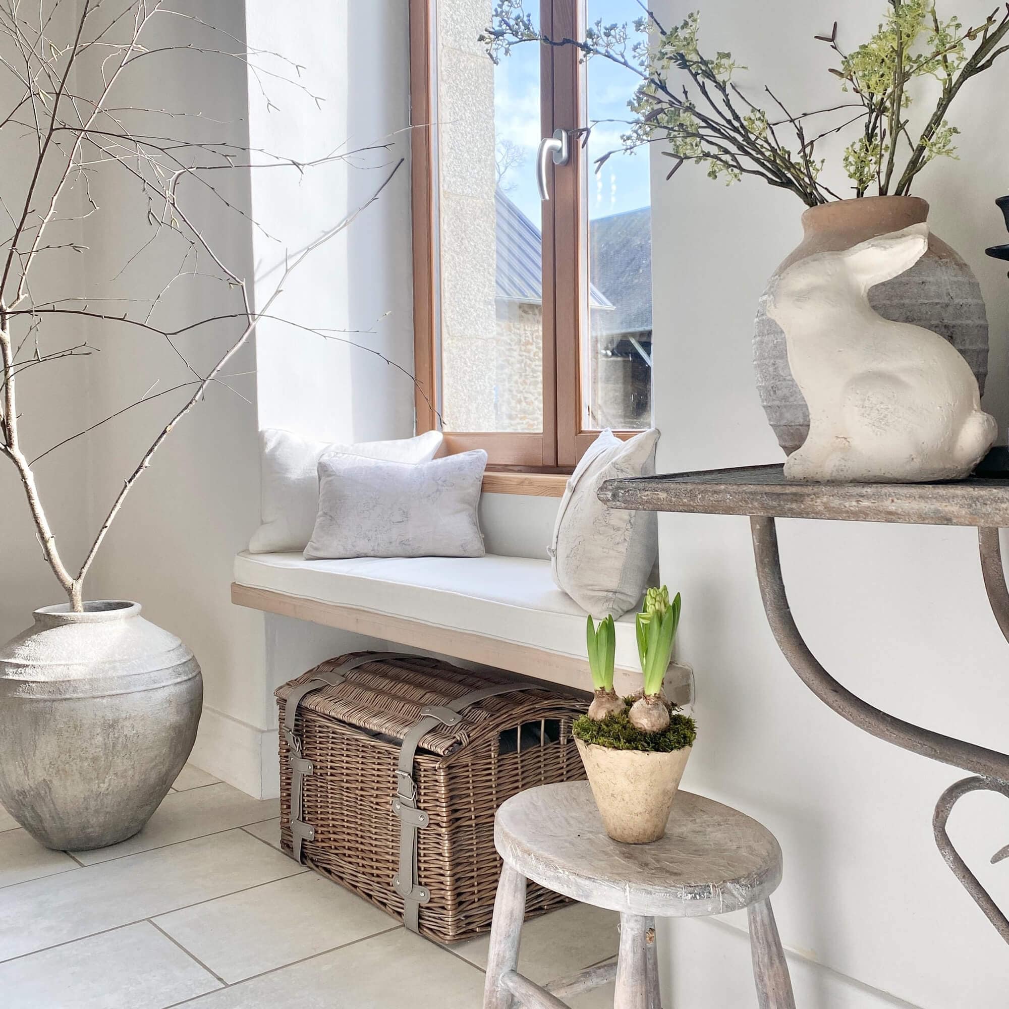 Coin cosy avec coussins blancs, coffre en osier et décoration lapin dans un intérieur lumineux