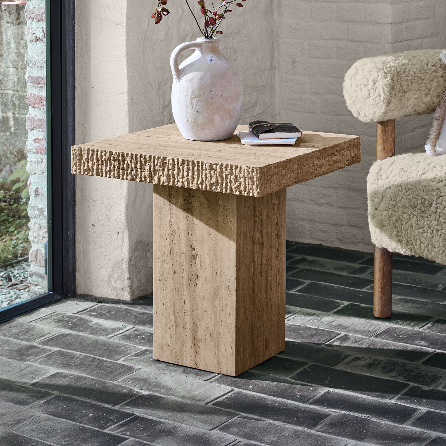 Table d'appoint carrée en travertin beige avec vase décoratif et livres posés dessus