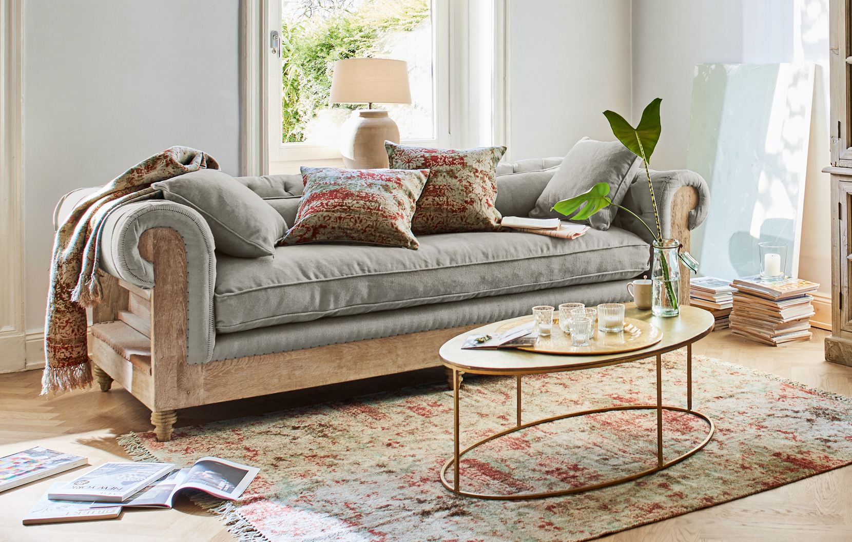 Canapé gris avec cadre en bois et tapis oriental dans un salon lumineux avec coussins décoratifs