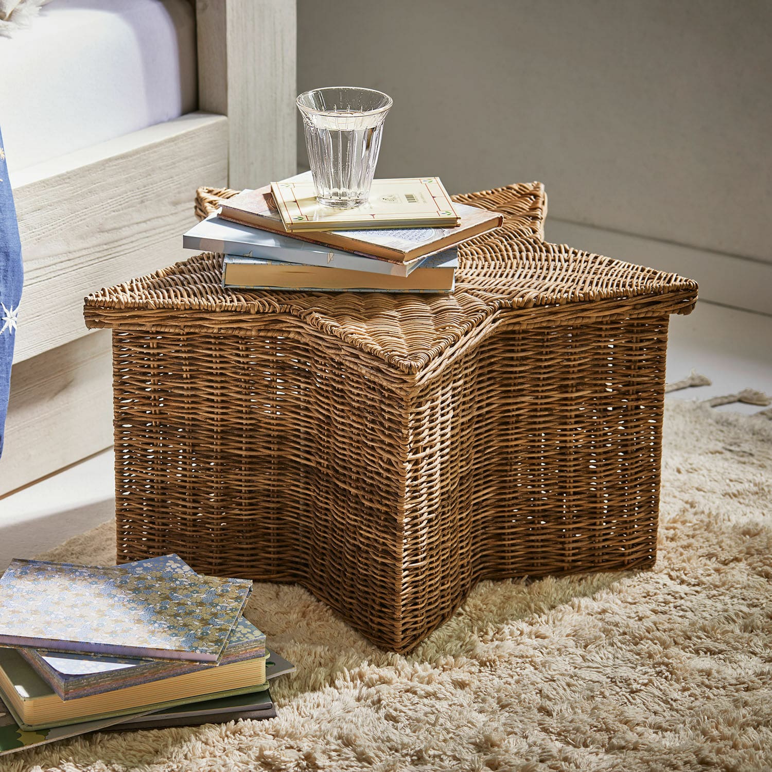 Panier Rivolina Panier en rotin en forme d'étoile sur tapis avec livres et verre d'eau, couleur naturelle