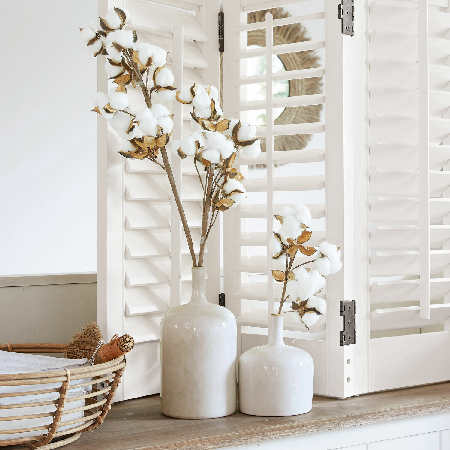 Lot de 2 vases Kurys Deux vases en céramique blanche avec branches de coton sur un meuble en bois devant des volets blancs