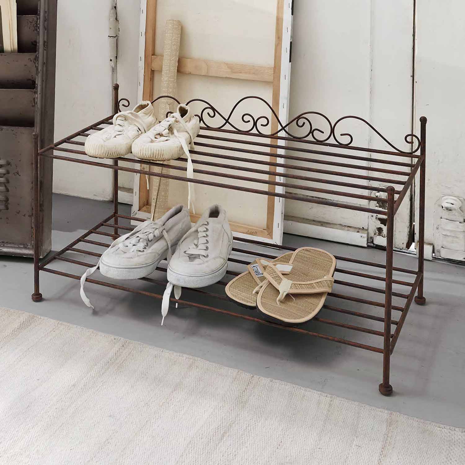 Étagère à chaussures en métal rouillé à deux niveaux avec baskets blanches et sandales beiges