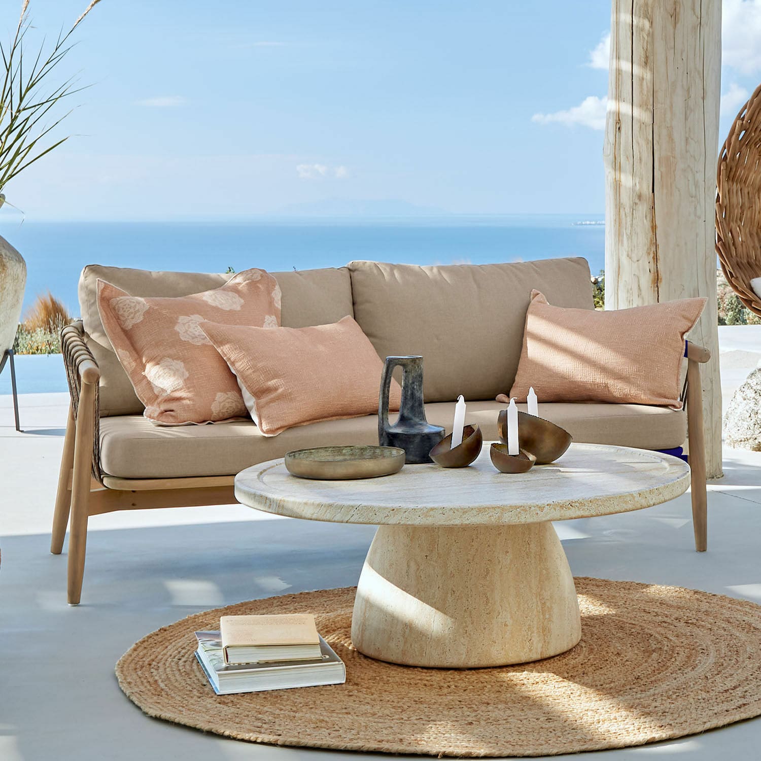Canapé FSC®-100% Thornwick Canapé beige avec coussins et table ronde en pierre sur terrasse avec vue sur la mer