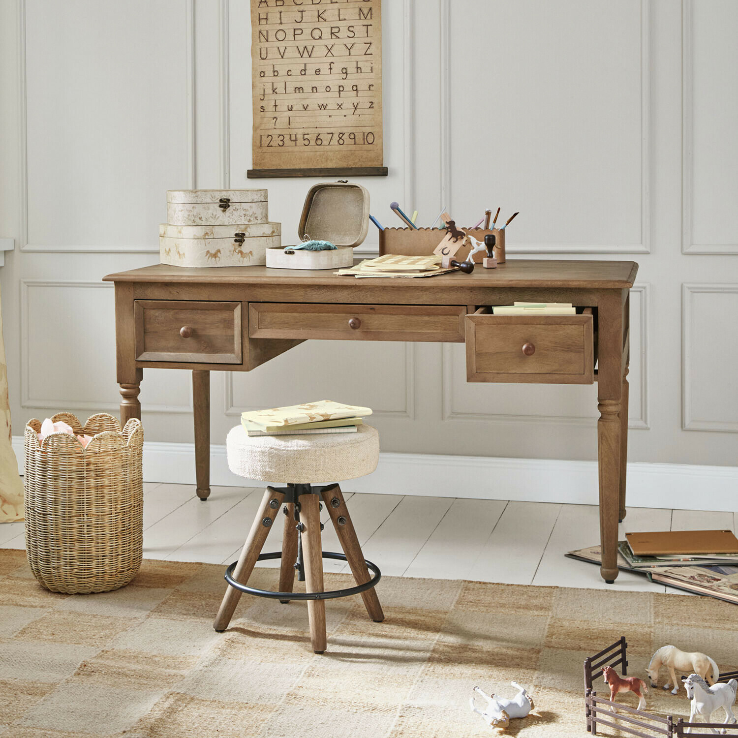Bureau pour enfant Norleigh Bureau en bois avec trois tiroirs et tabouret beige dans une pièce claire avec décorations éducatives
