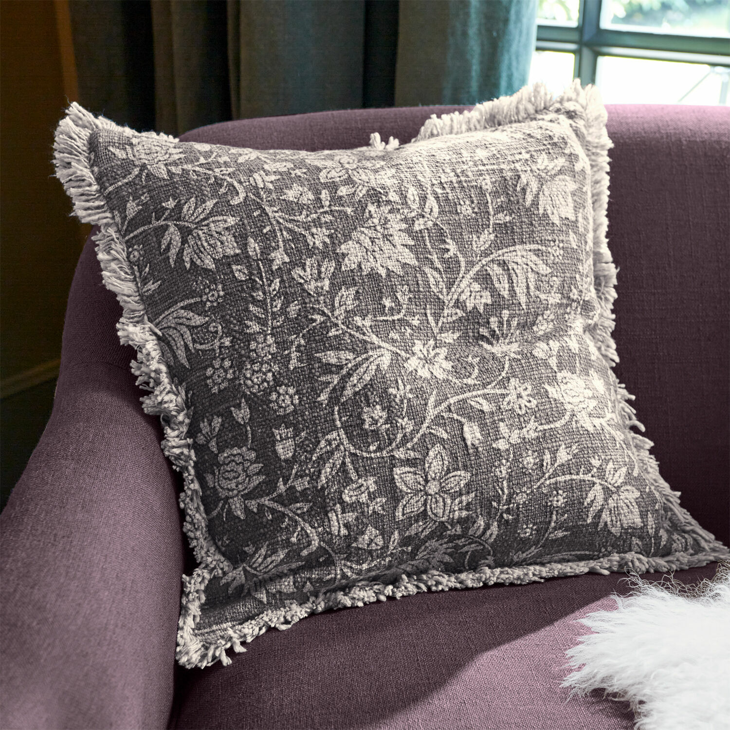 Housse de coussin Jorelise Coussin décoratif gris avec motif floral blanc et franges sur canapé violet
