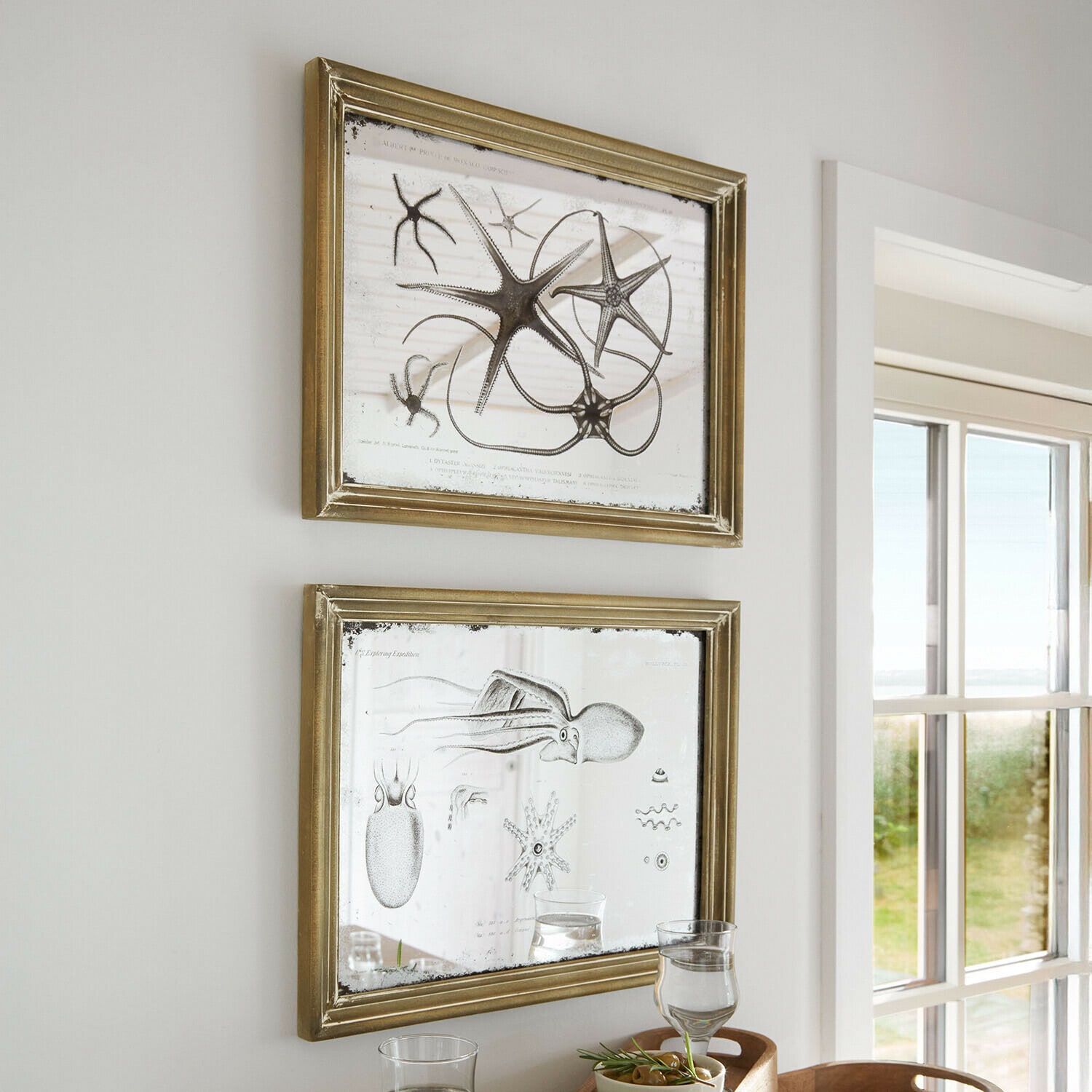 Lot de 2 miroirs à motifs Marivelles Deux cadres dorés avec miroir et illustrations marines, décoration murale dans une pièce lumineuse