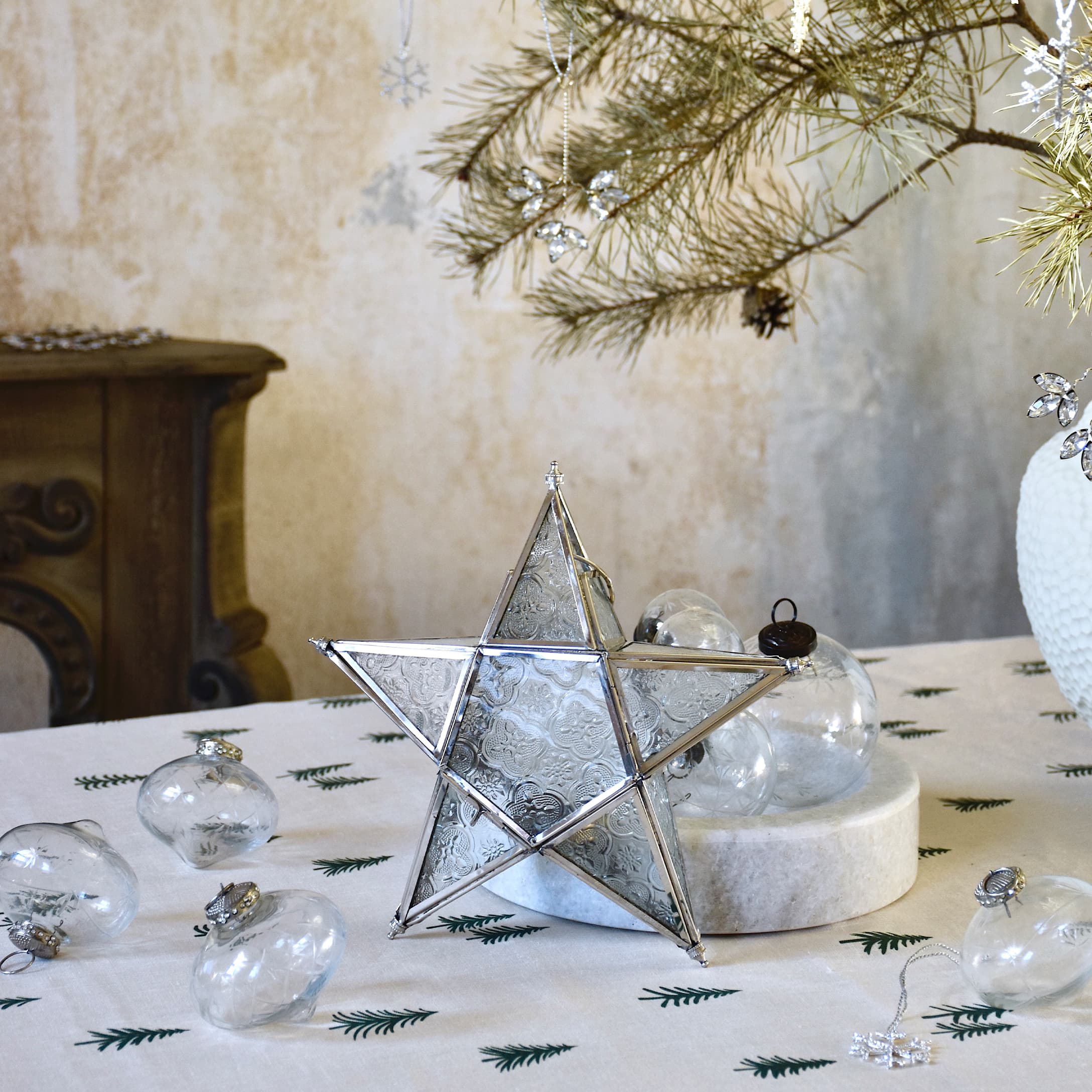 Décoration étoile en verre avec cadre métallique sur une table de Noël avec ornements transparents