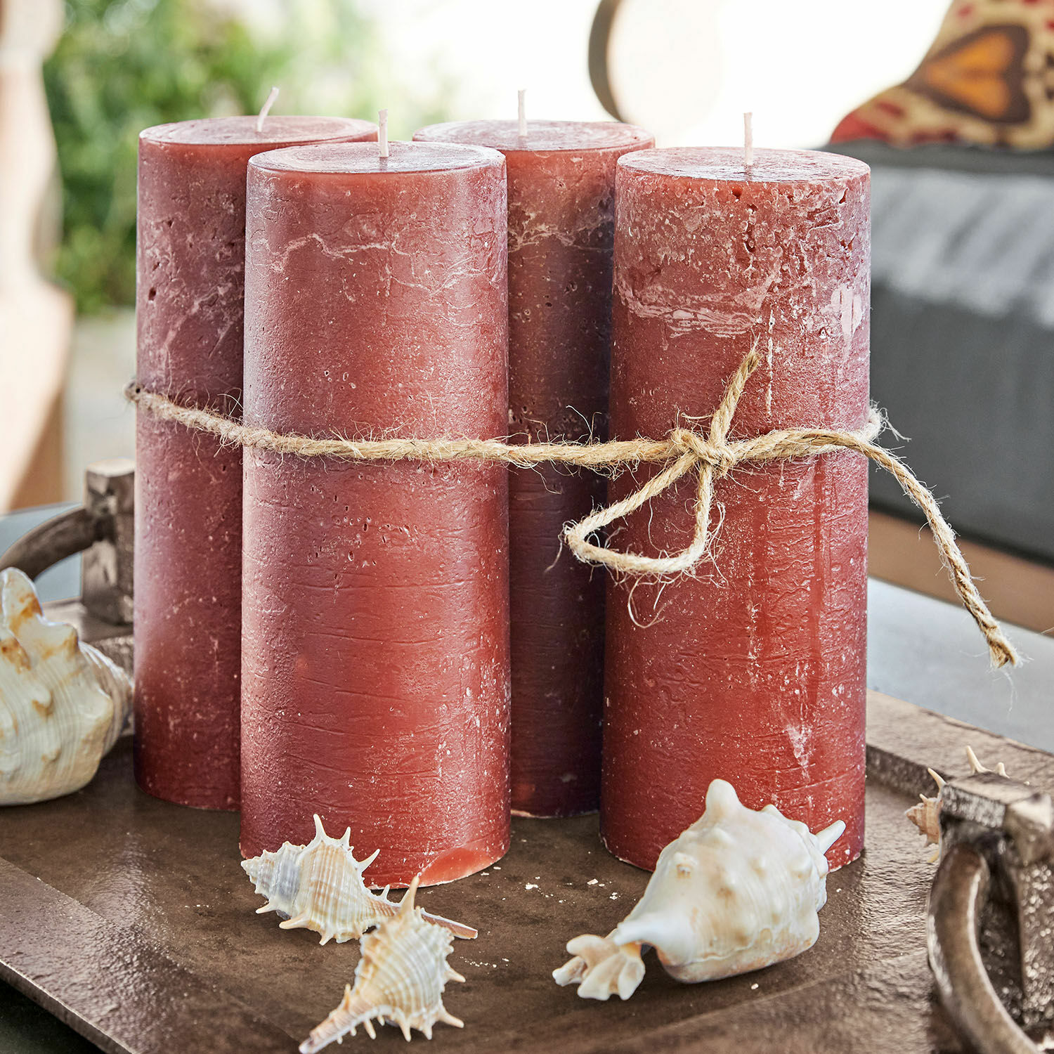 Lot de 4 bougies Homel Quatre bougies rouges en cire avec corde naturelle sur un plateau décoratif avec coquillages