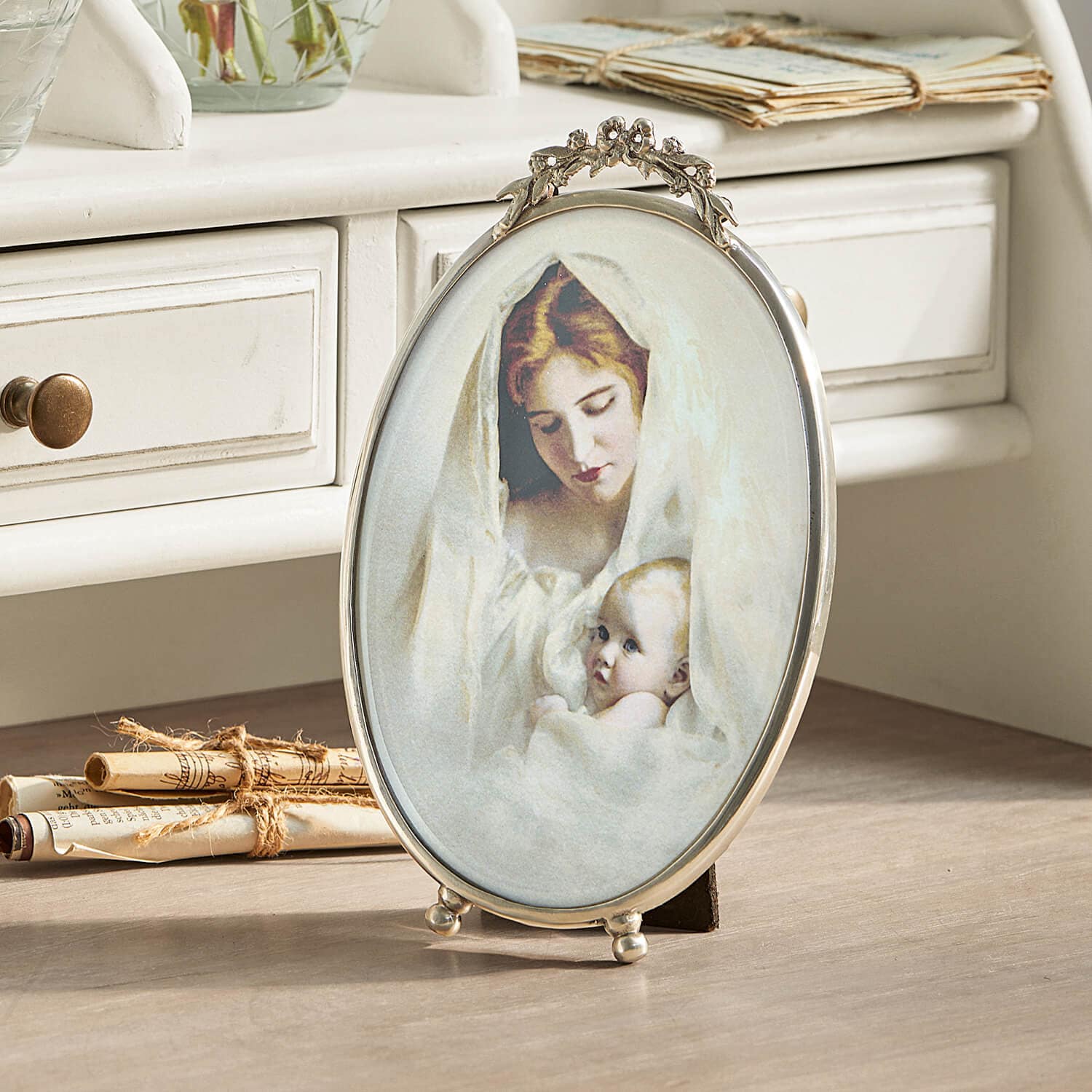 Cadre photo ovale en métal avec image d'une mère et son bébé enveloppés de tissu blanc