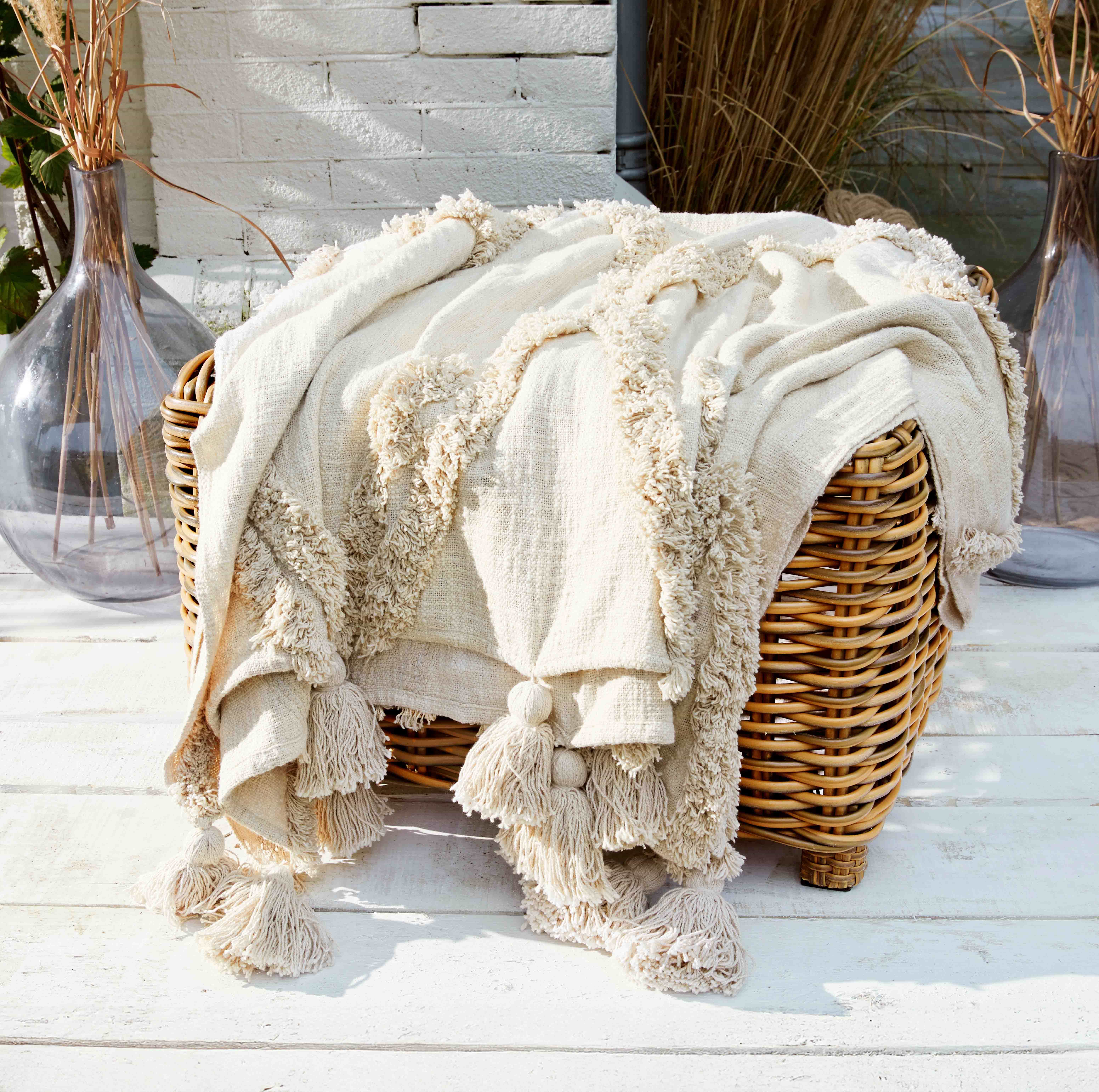 Plaid crème en tissu doux avec franges sur fauteuil en osier, décoration intérieure et confort