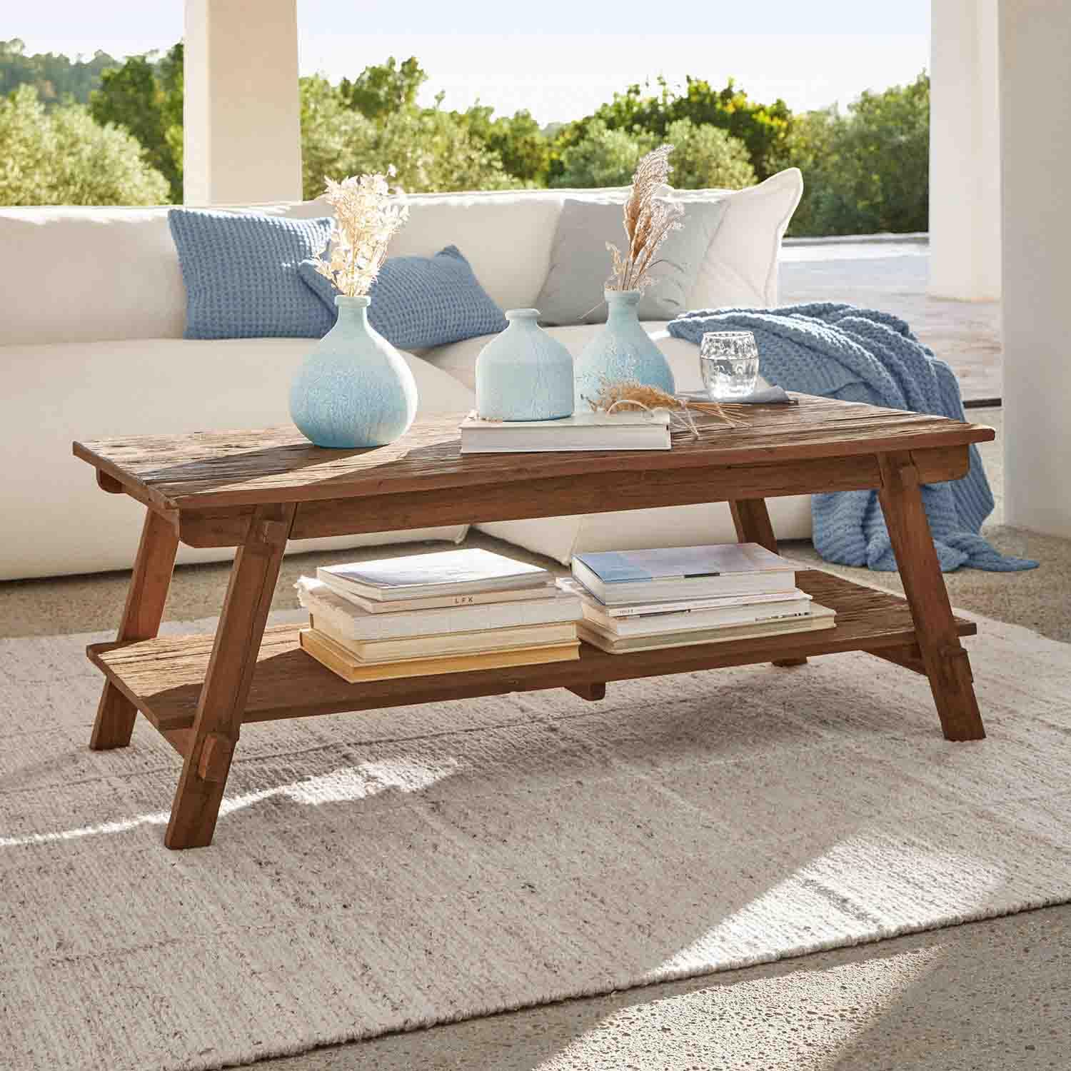 Table basse en bois d'acacia brun avec étagère et vases décoratifs bleus dans un salon lumineux