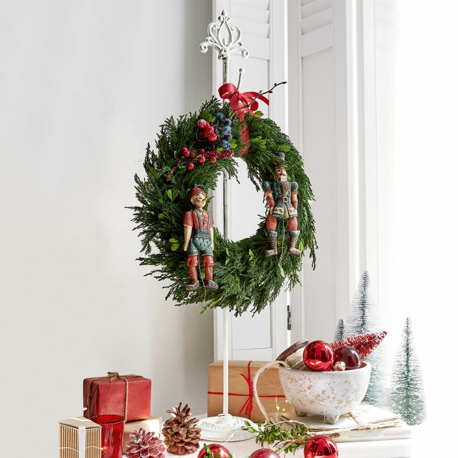 Support pour couronne Irulan Couronne de Noël en branches vertes avec baies rouges et bleues et figurines en bois sur support blanc