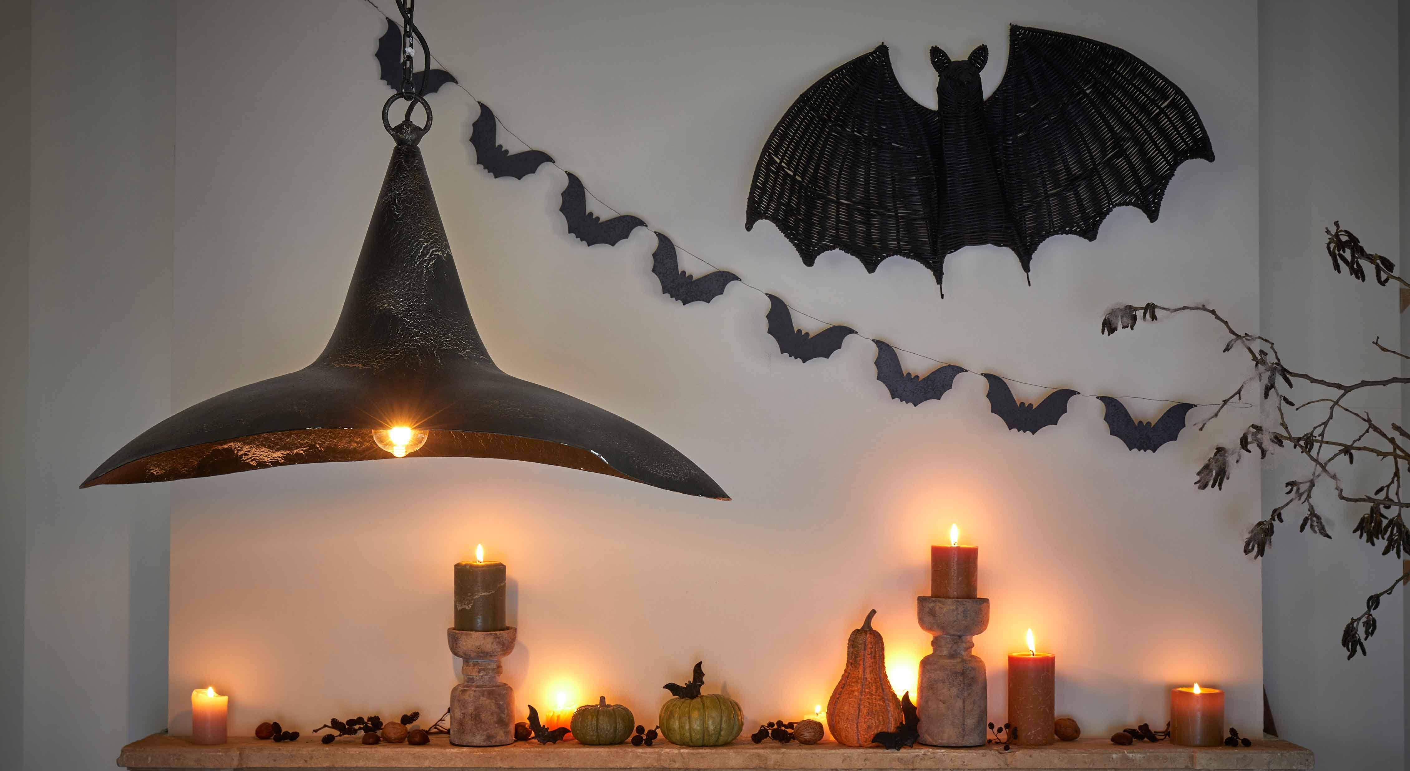 Décoration d'Halloween avec bougies noires, citrouilles et lampe en métal noir sur mur avec chauves-souris