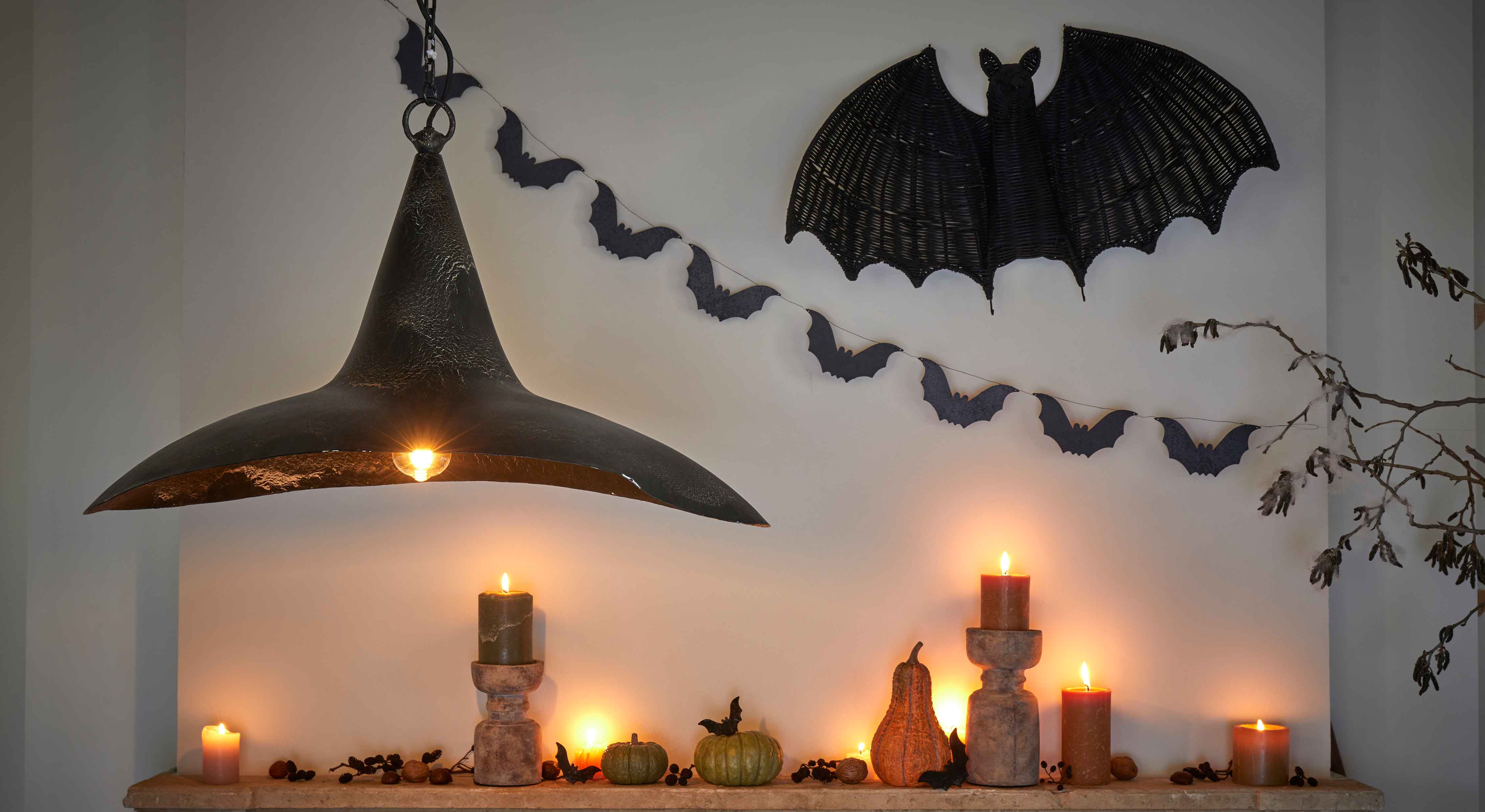 Décoration d'Halloween avec bougies noires, citrouilles et lampe en métal noir sur mur avec chauves-souris