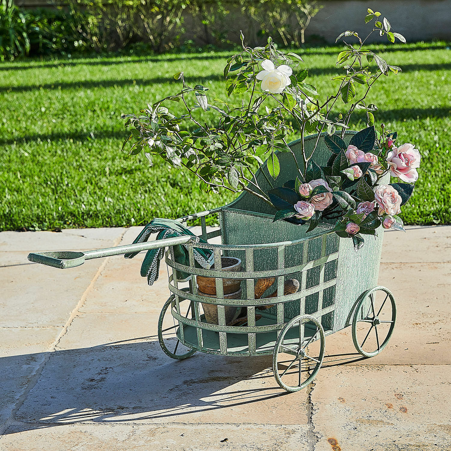 Jardinière Pavignac Chariot de jardin vert en métal avec roses et pots sur terrasse, outils de jardinage