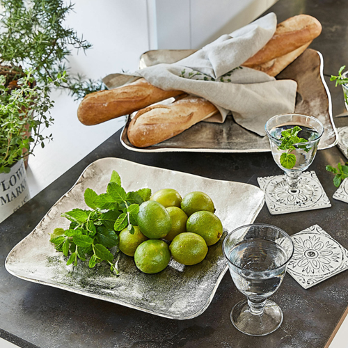 Plateau carré en métal argenté avec citrons verts et menthe sur table avec baguettes et verres d'eau