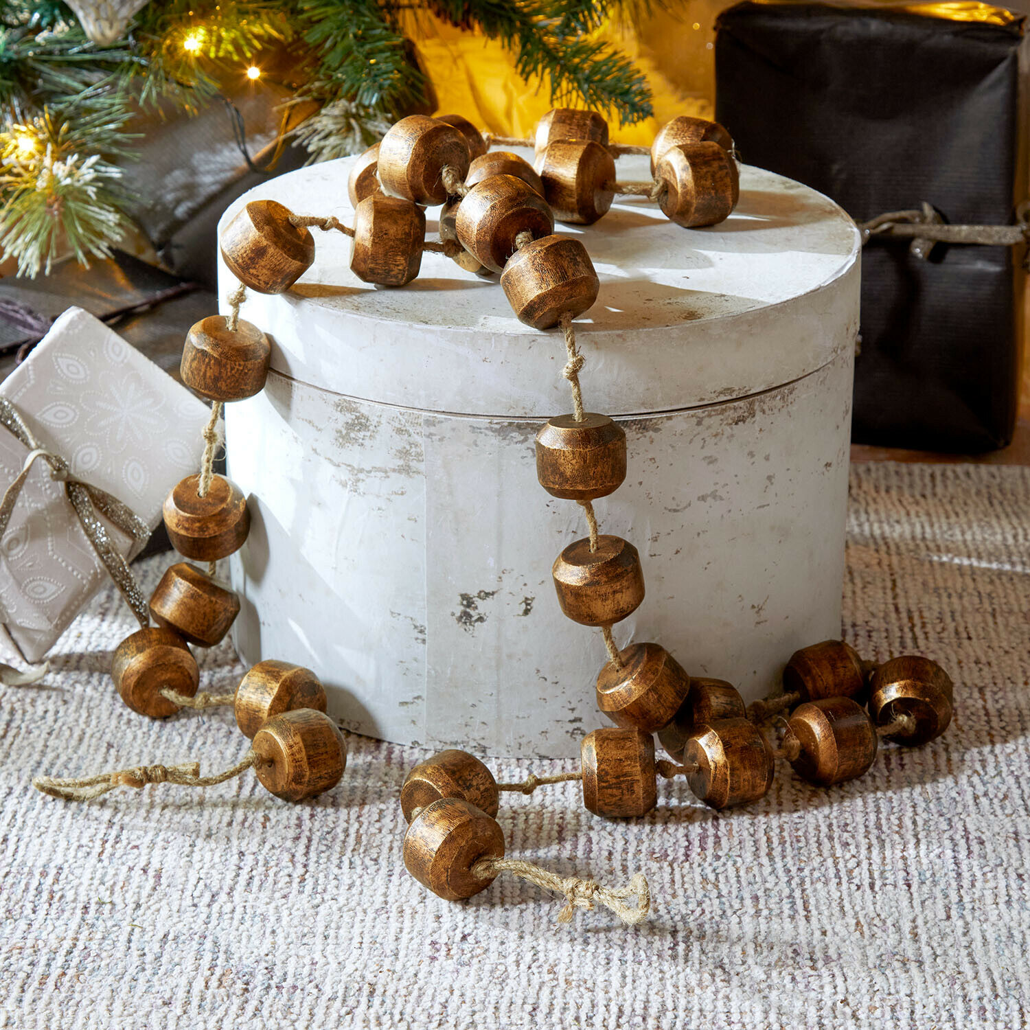 Guirlande Caralinas Guirlande décorative en perles de bois marron posée sur un support clair, décoration festive