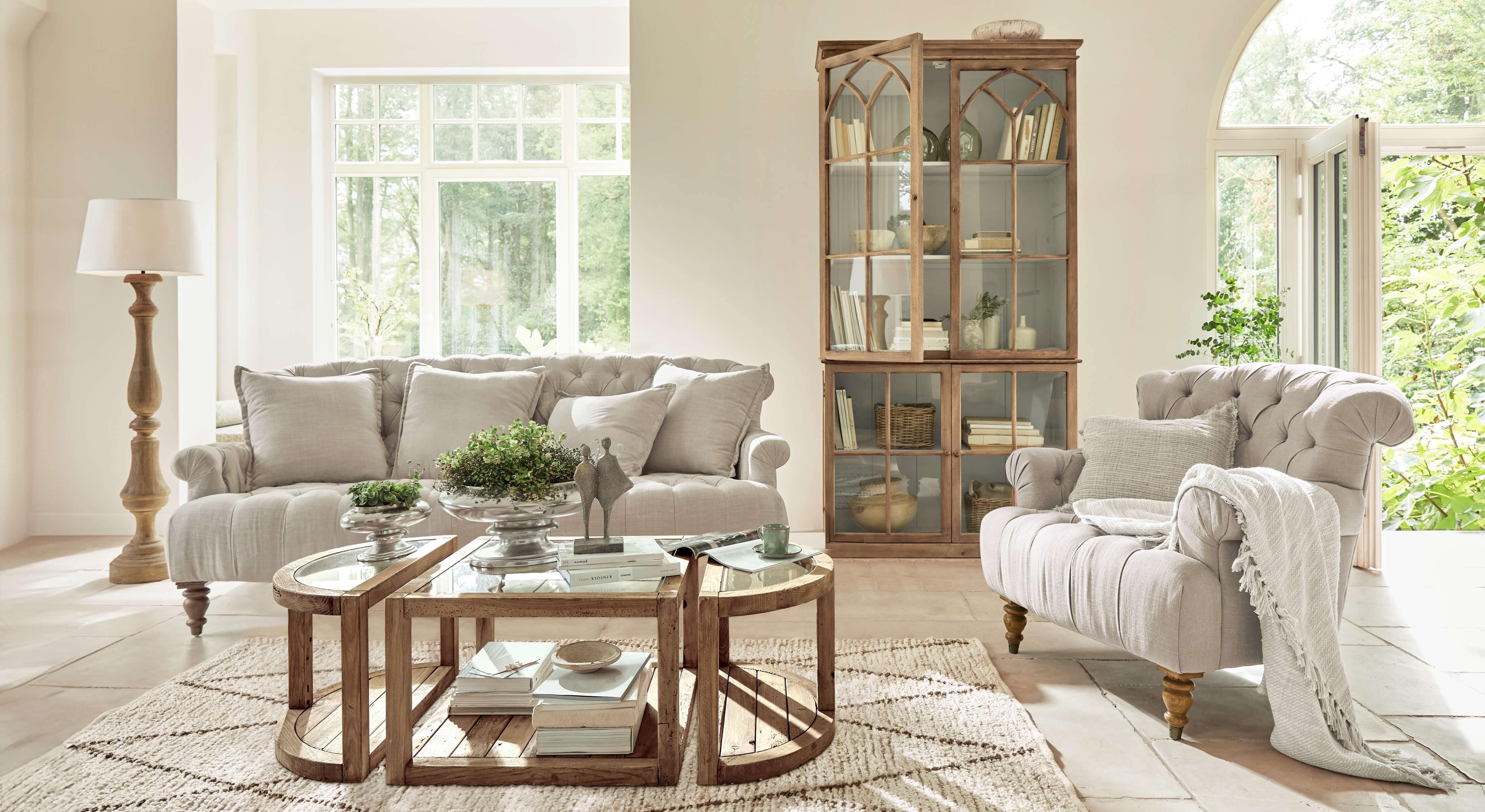 Salon lumineux avec canapé et fauteuil beige en tissu, meubles en bois et table basse rustique