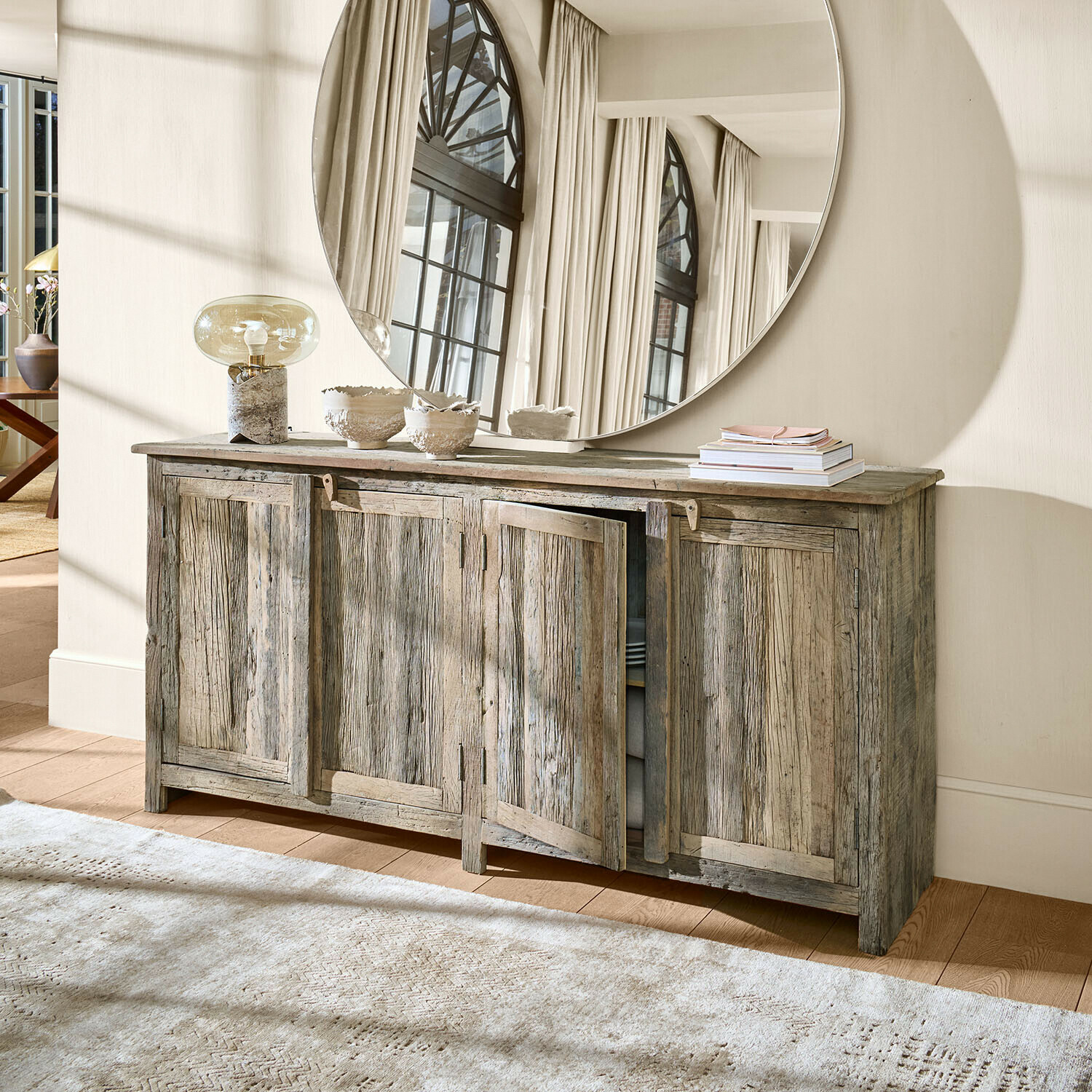 Buffet rustique en bois gris avec quatre portes et grand miroir rond décoratif au mur