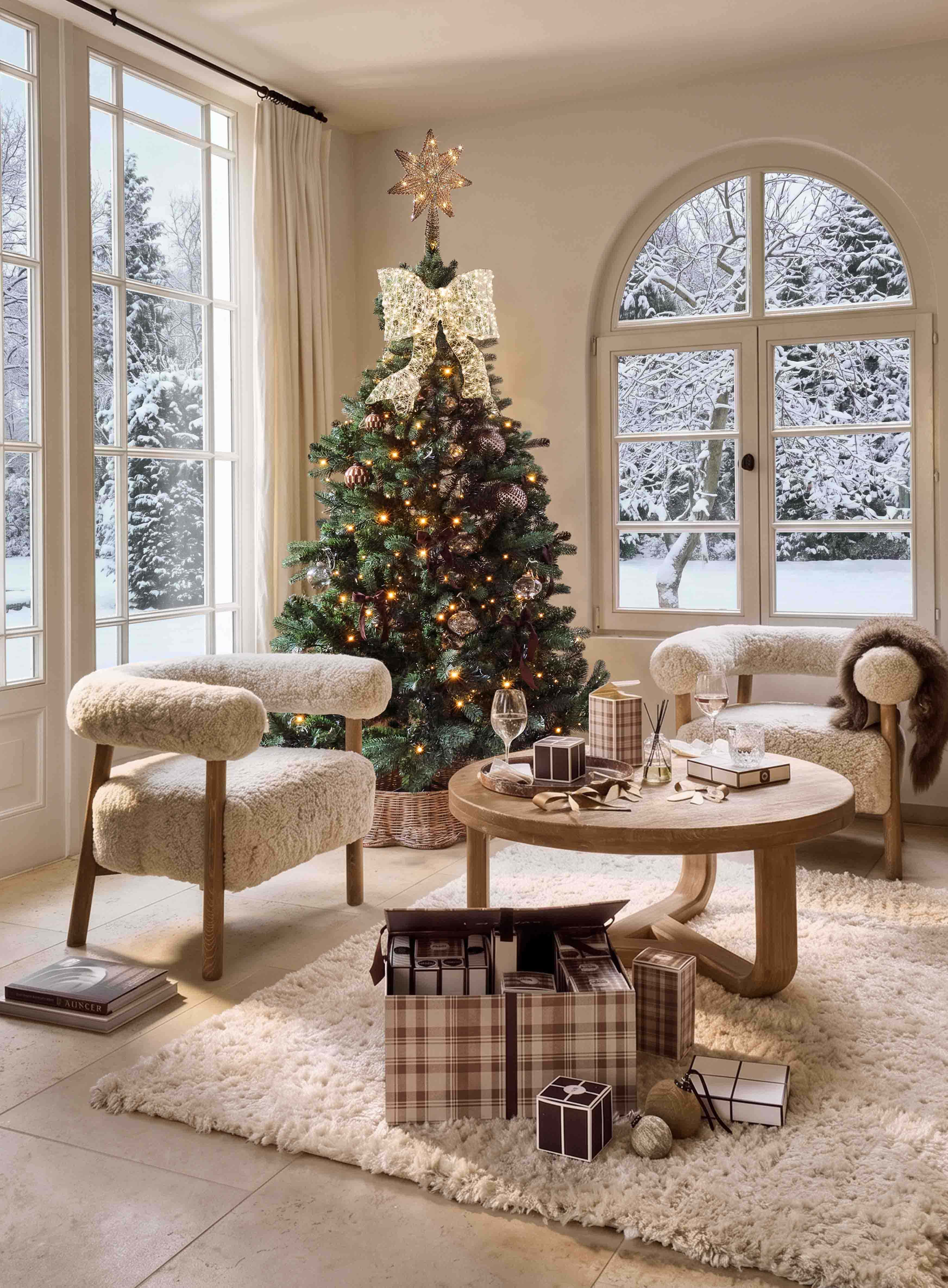 Sapin de Noël décoré avec étoile lumineuse et grand nœud dans un salon chaleureux avec vue sur jardin enneigé