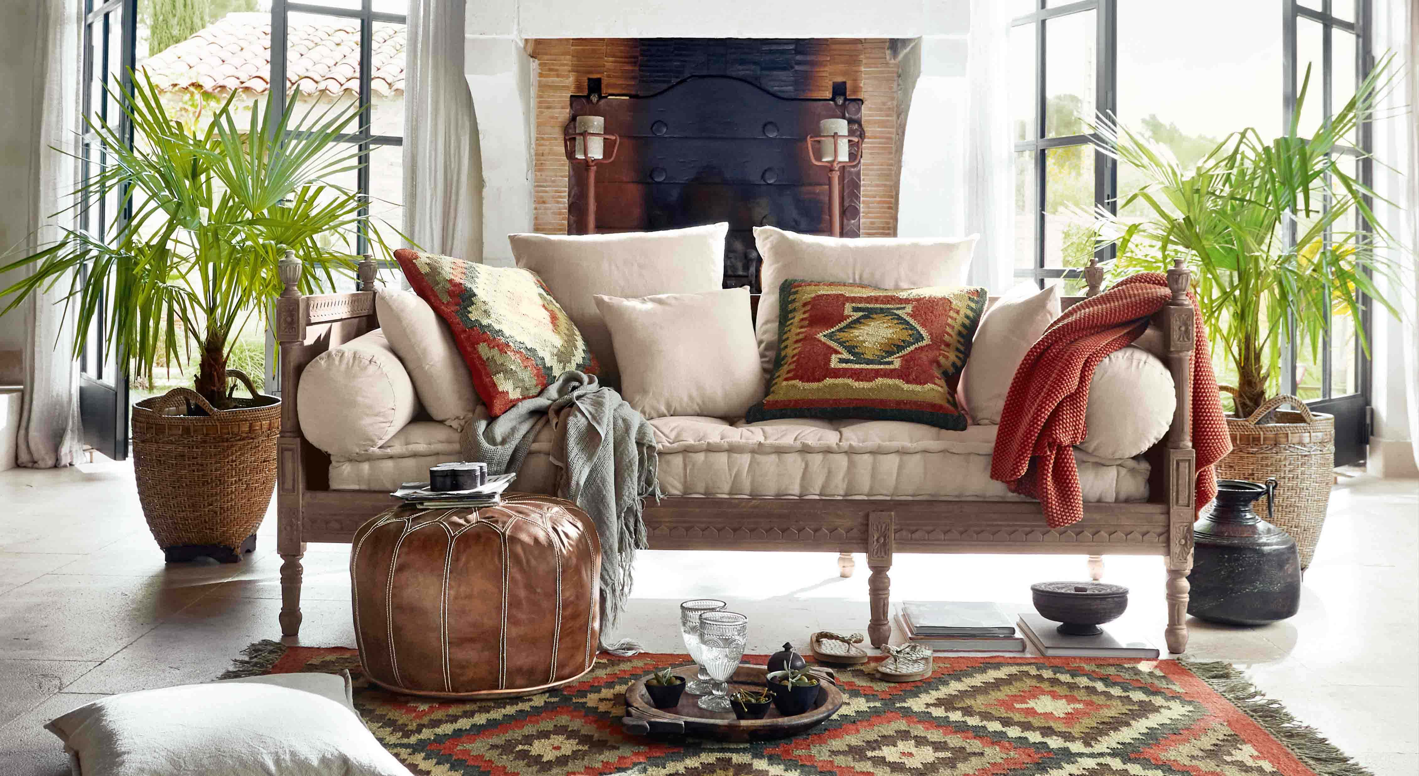 Canapé avec revêtement beige clair et cadre en bois, coussins colorés et plaid style bohème dans un salon lumineux