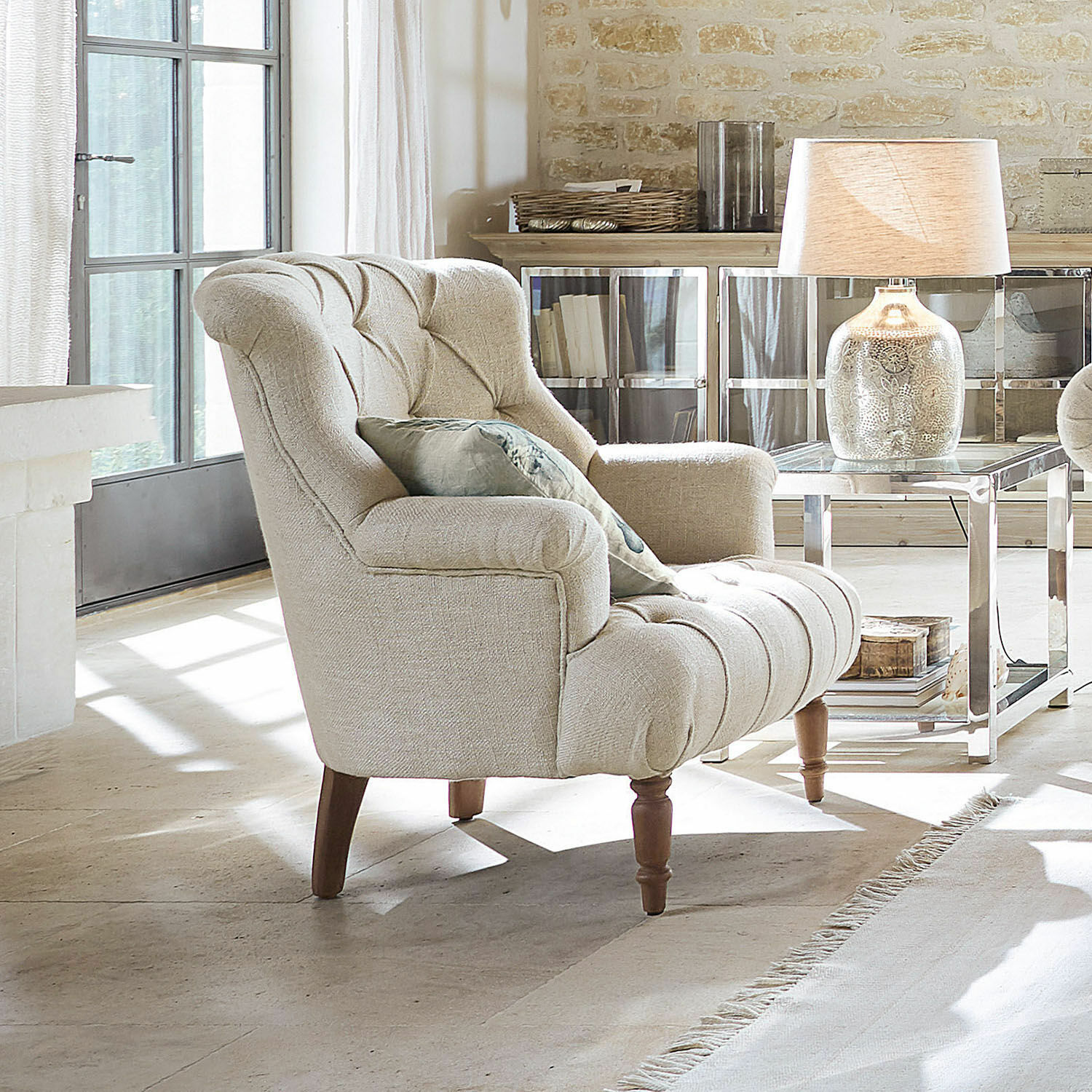 Fauteuil Parranquet Fauteuil beige rembourré avec pieds en bois dans un salon lumineux avec lampe et table
