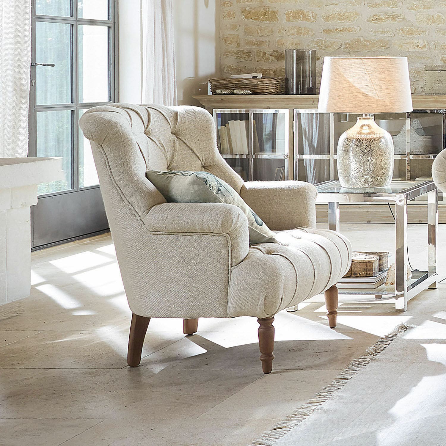 Fauteuil Parranquet Fauteuil beige rembourré avec pieds en bois dans un salon lumineux avec lampe et table