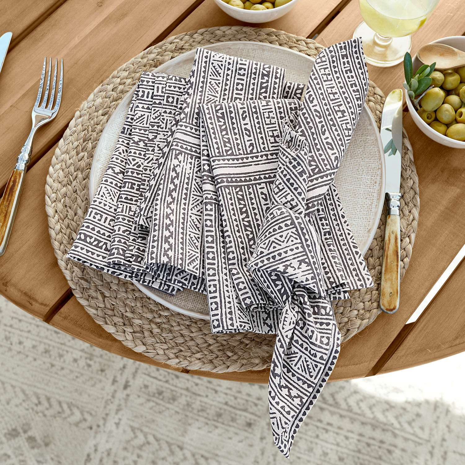 Lot de 4 serviettes de table Quentinelle Serviettes en lin à motif noir et blanc posées sur un dessous de plat tressé en bois