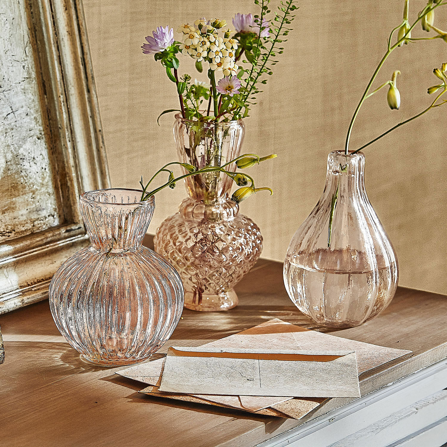 Lot de 3 vases Faunelle Trois vases en verre transparent avec des fleurs sur une surface en bois dans un style vintage