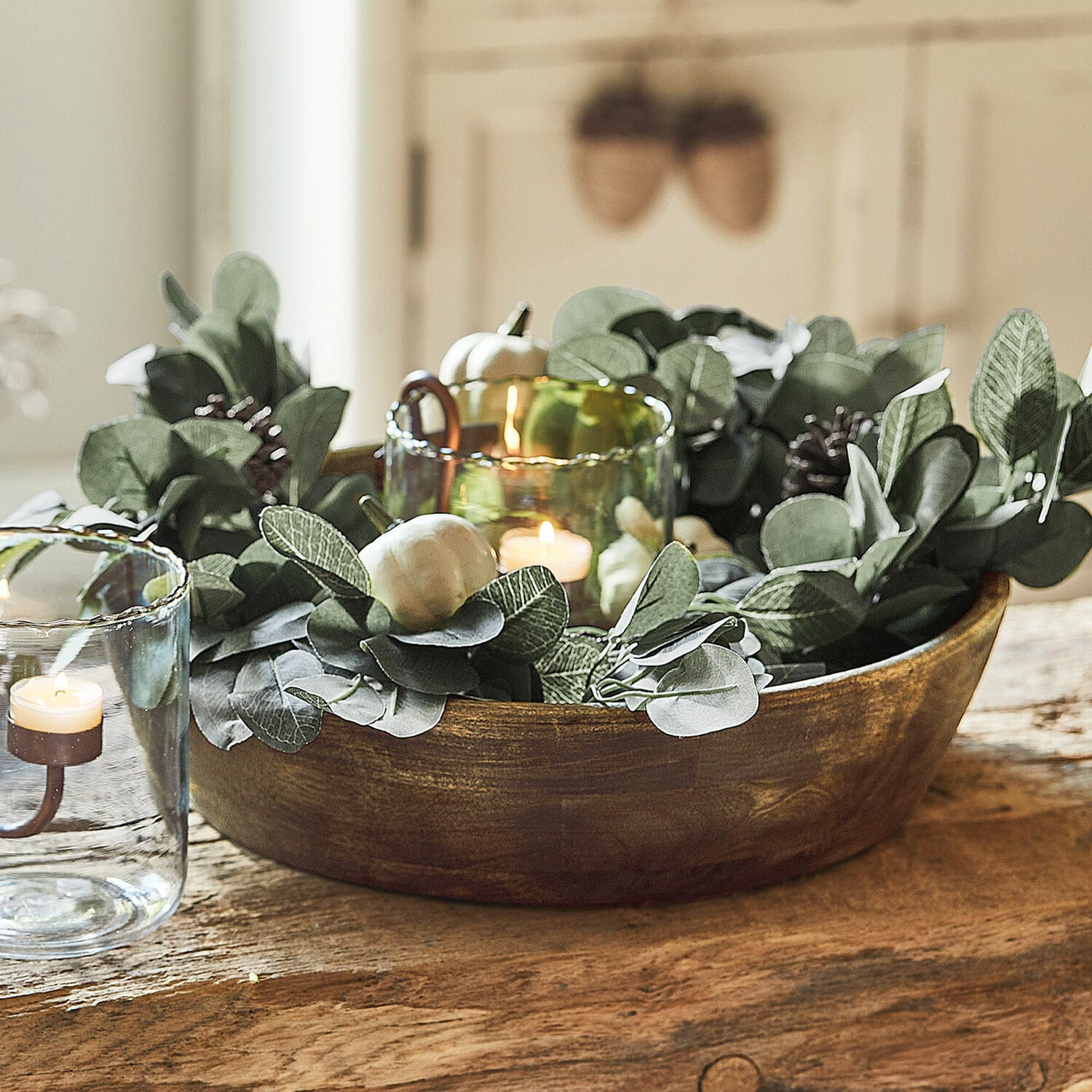 Coupe Crisfield Bol en bois décoratif avec feuillage vert et bougies dans des photophores en verre sur une table
