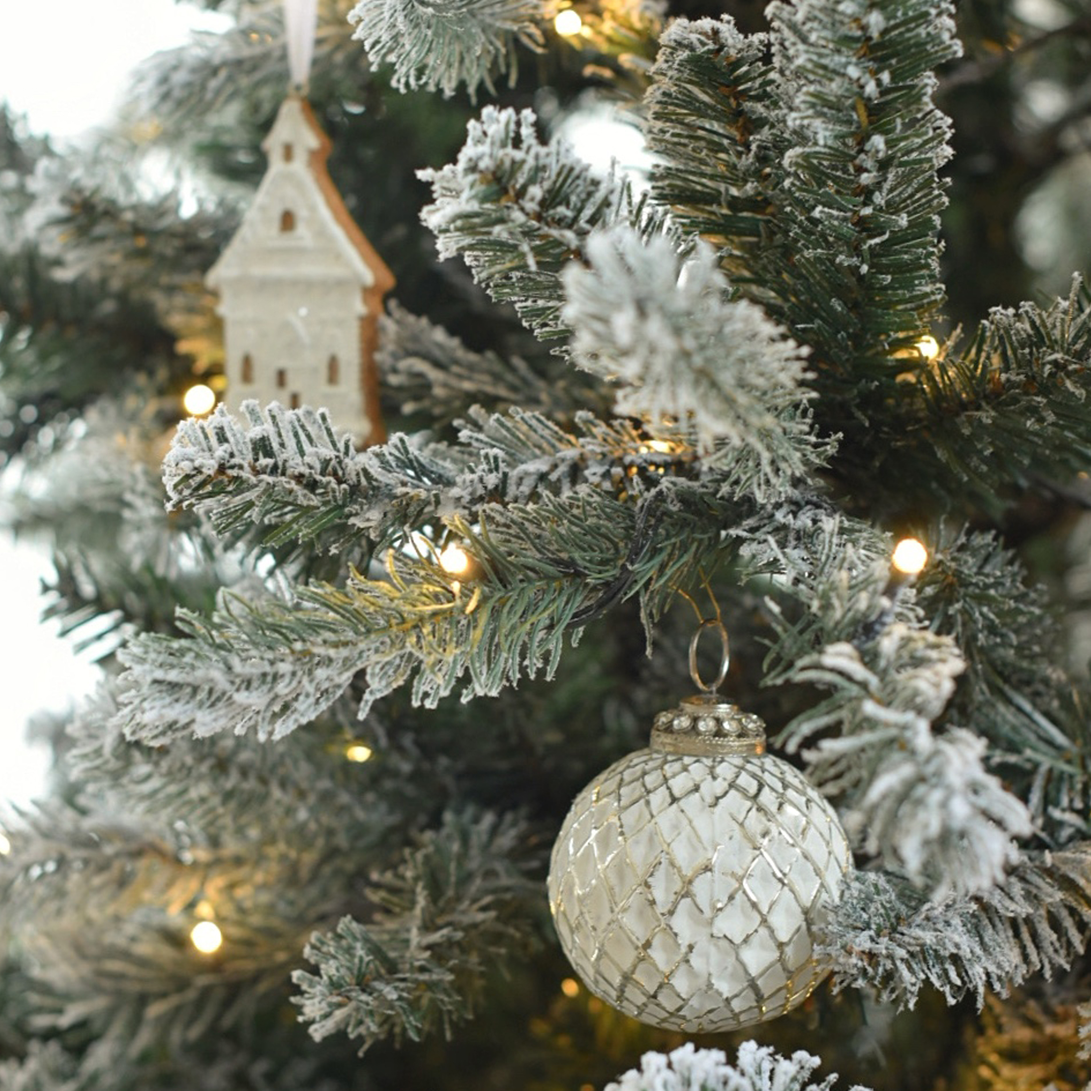 Boule de Noël en verre blanc à motif quadrillé sur sapin enneigé avec lumières LED et décoration en bois