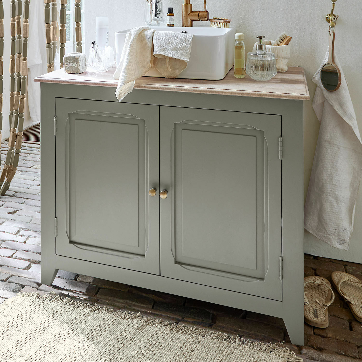 Meuble et vasque Bastanès Meuble de salle de bain gris avec plan en bois et lavabo blanc, accessoires de salle de bain posés dessus
