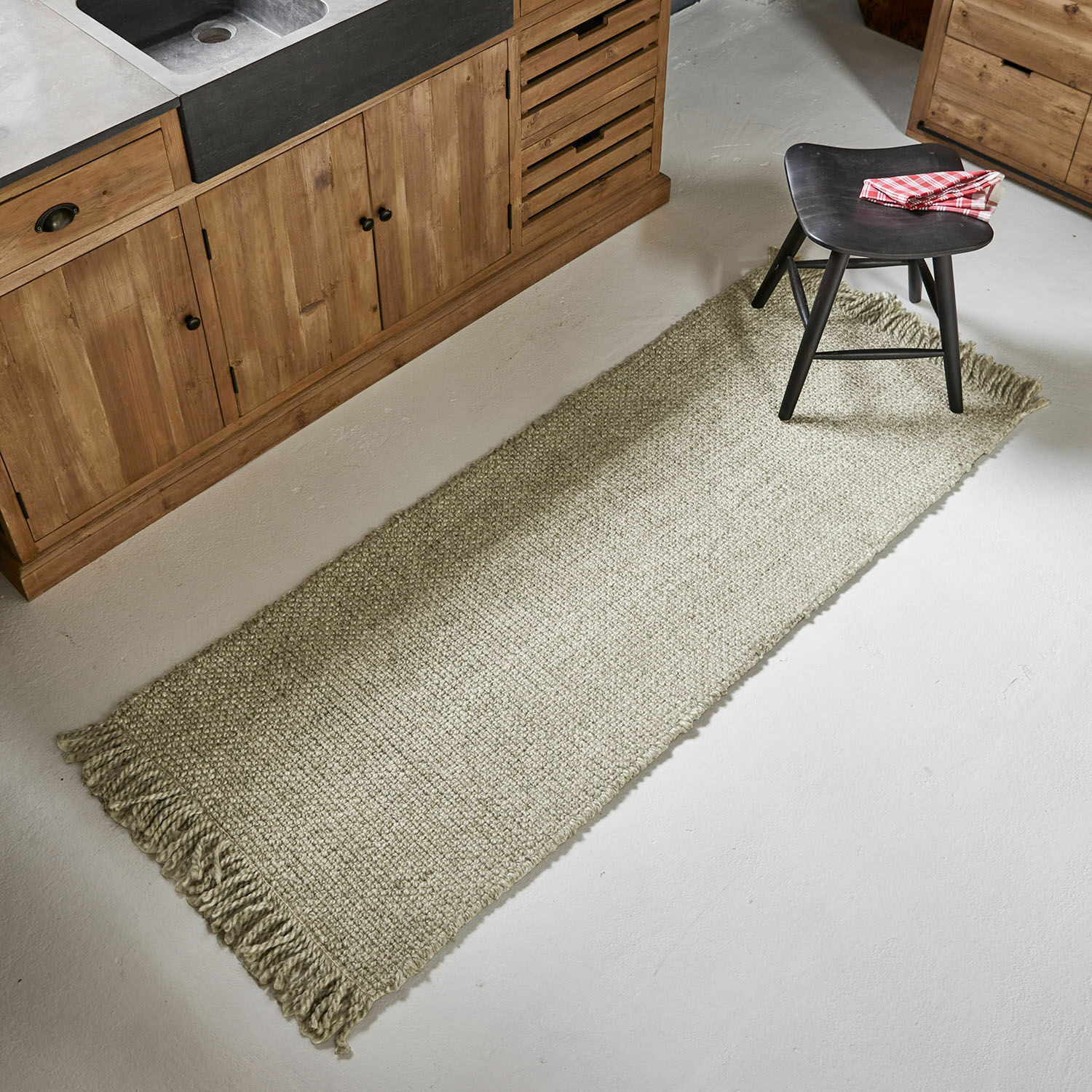 Tapis long Maravéa Tapis beige à franges en matériau naturel posé sur le sol d'une cuisine avec meubles en bois