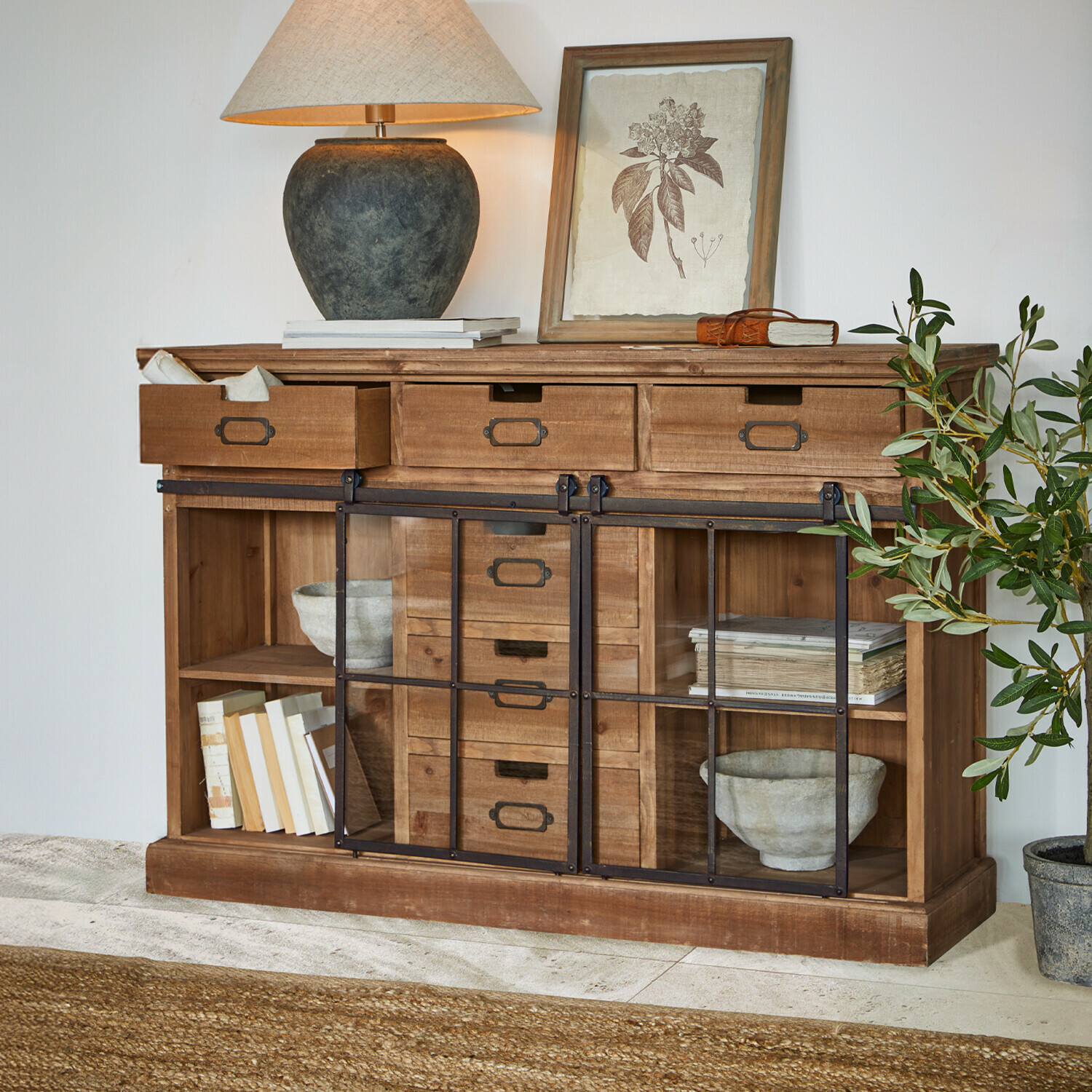 Buffet en bois avec tiroirs et portes vitrées, décoré d'une lampe et d'une plante, style rustique