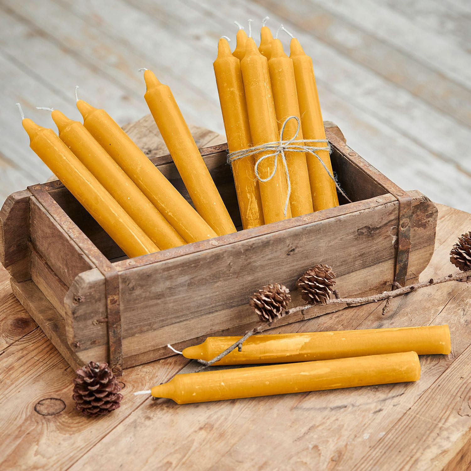 Lot de 12 bougies Bauceau Lot de bougies jaunes en cire d'abeille dans une caisse en bois sur une table rustique