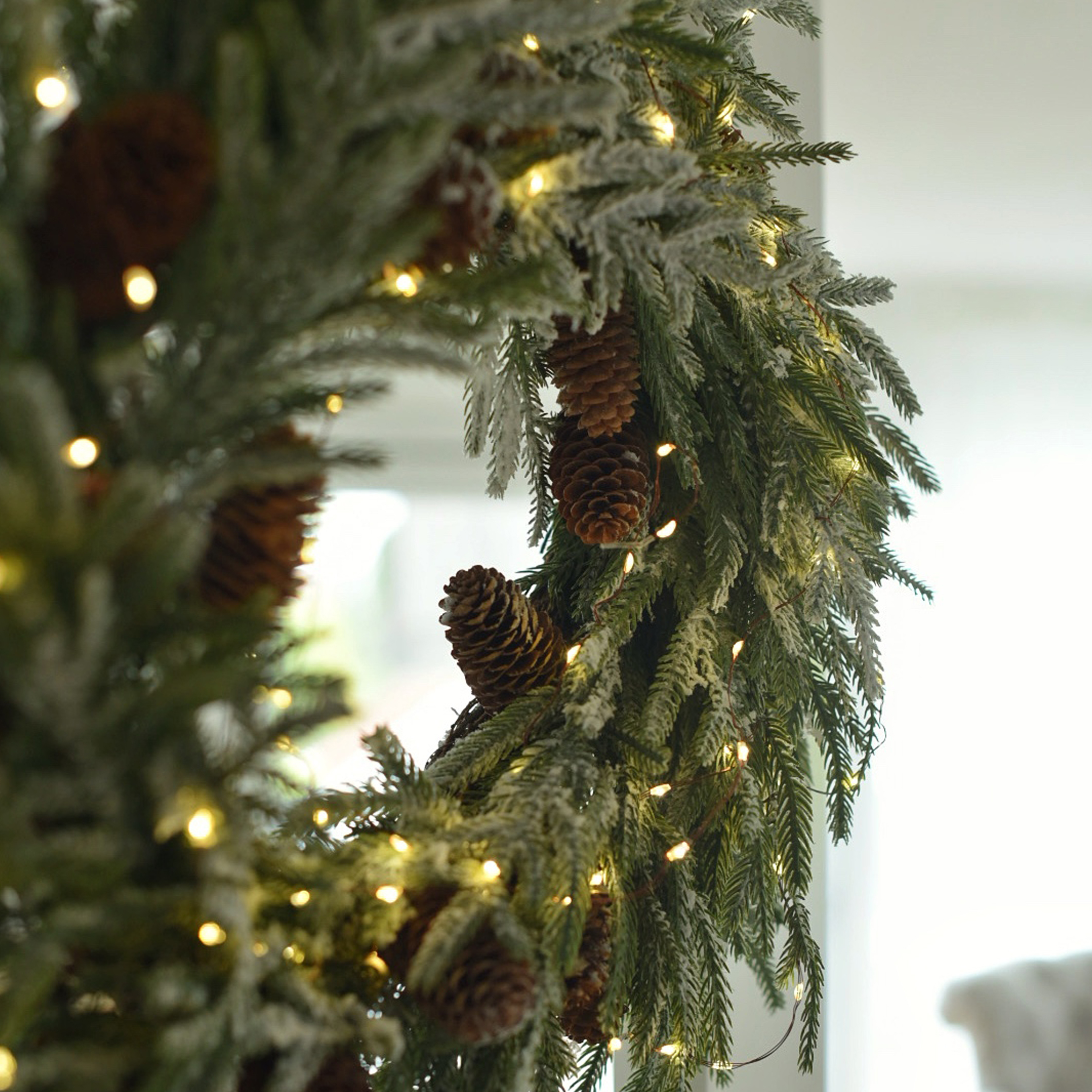 Couronne de Noël en branches vertes avec pommes de pin et guirlande lumineuse LED pour décoration hivernale