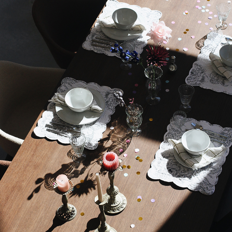 Table élégamment dressée avec vaisselle blanche en céramique et bougies sur plateau en bois
