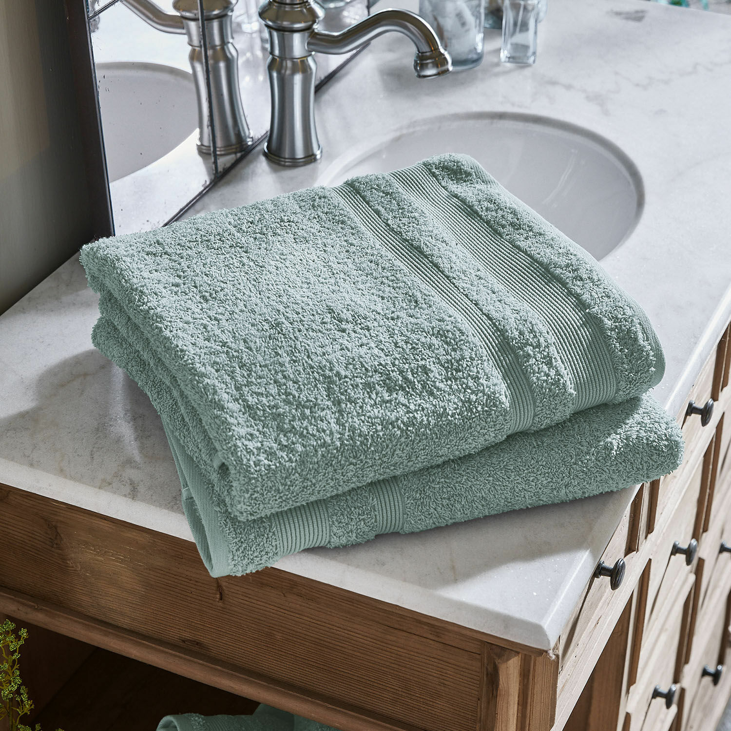 Lot de 2 draps de bain Bourogne Serviettes vertes en coton douces posées sur un lavabo en marbre avec meuble en bois dans la salle de bain