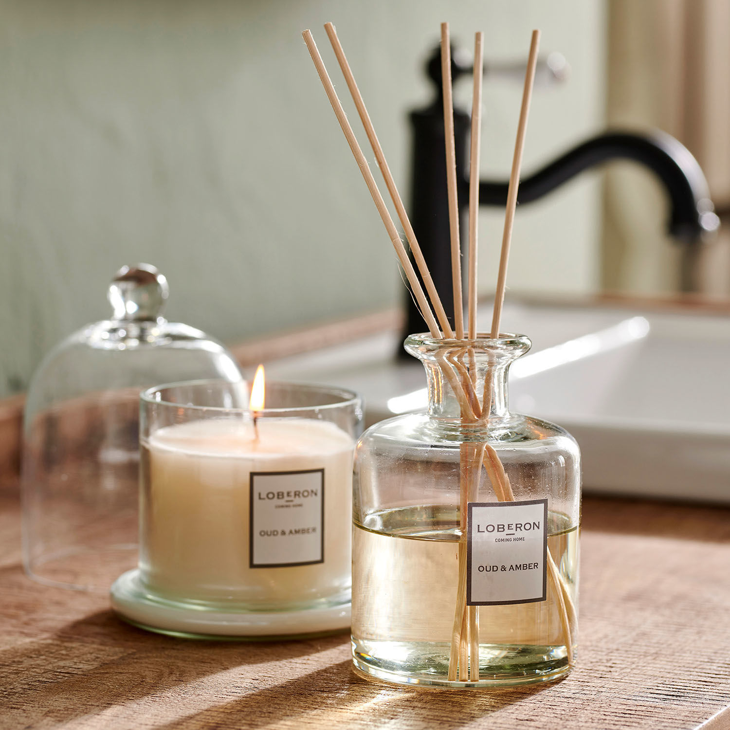 Coffret de senteurs Vanis Bougie et diffuseur de parfum Oud & Amber en verre sur un comptoir en bois dans une salle de bain