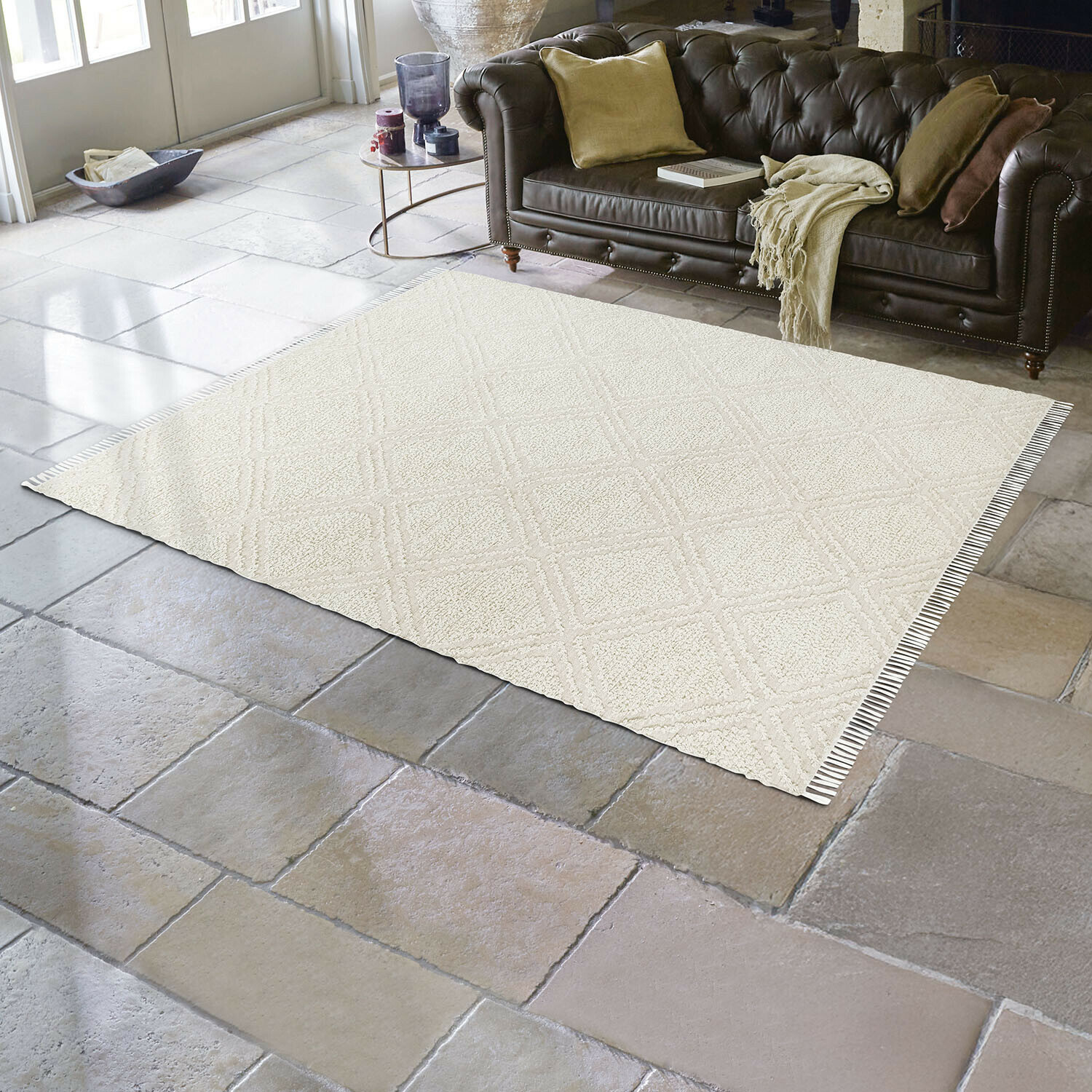 Tapis d'intérieur et d'extérieur Bruand Tapis beige à motif géométrique sur sol en pierre dans un salon avec canapé en cuir marron
