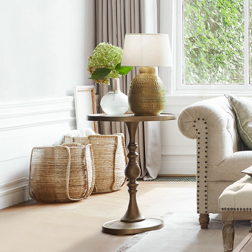 Table d'appoint ronde en métal brun avec lampe et décoration dans un salon lumineux
