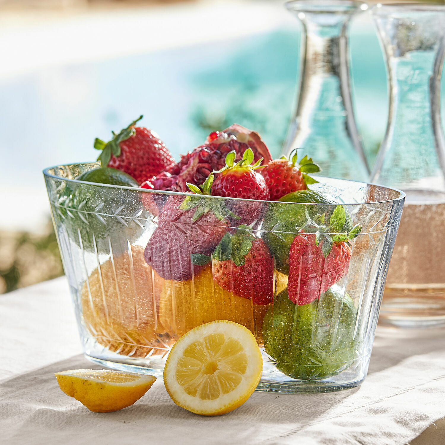 Coupe Malinda Bol en verre transparent avec fraises, citrons verts et citron sur une nappe claire, décoration de table