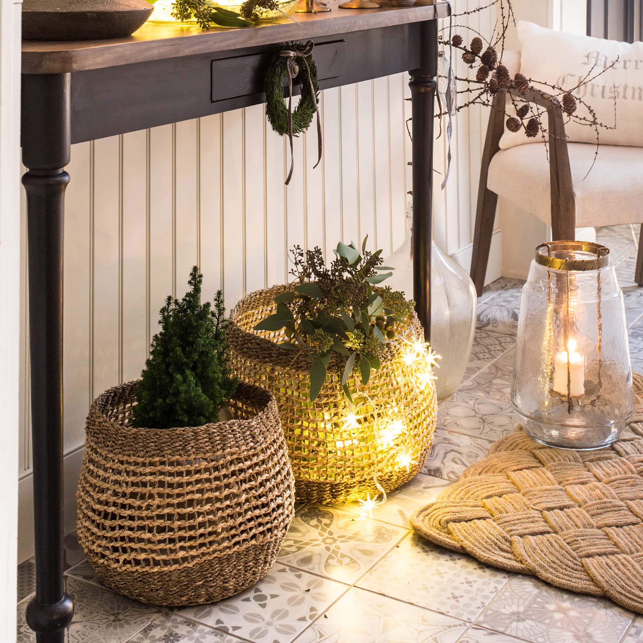 Paniers décoratifs en matériau naturel avec plantes vertes et guirlandes lumineuses dans un intérieur chaleureux