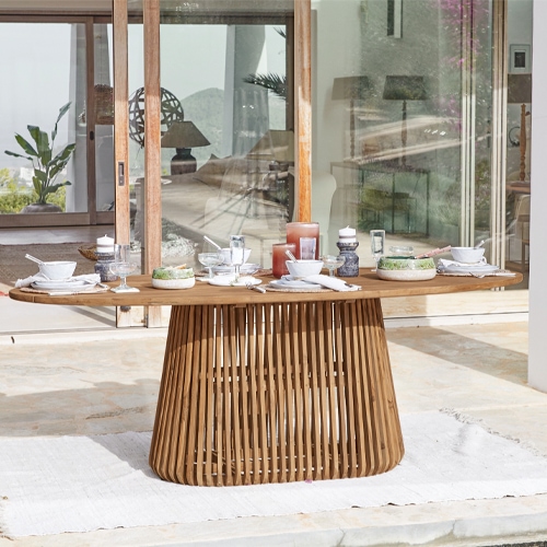 Table ovale en bois de teck sur terrasse avec vaisselle et décorations, mobilier d'extérieur