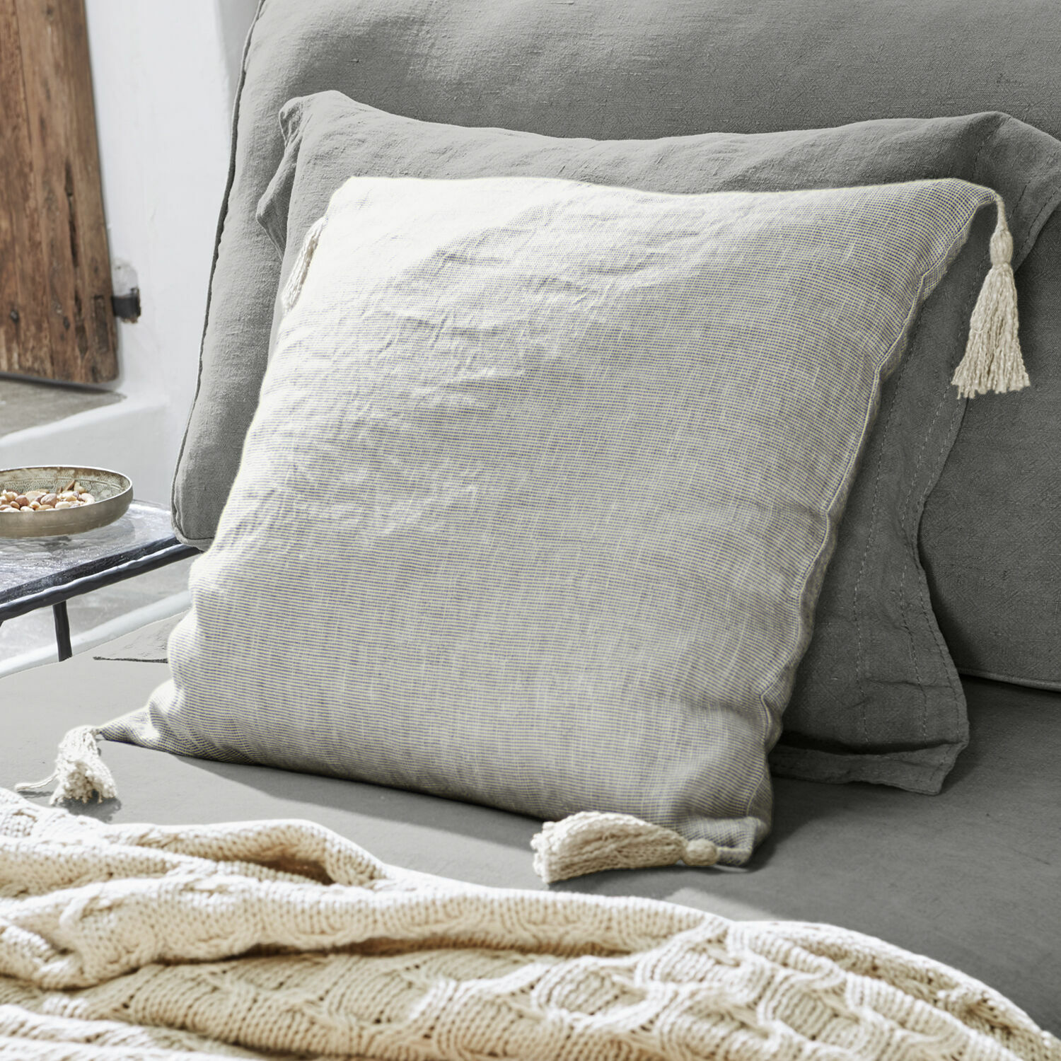 Housse de coussin Loubna Coussin décoratif beige en lin avec pompons sur canapé gris, accessoire cosy pour salon