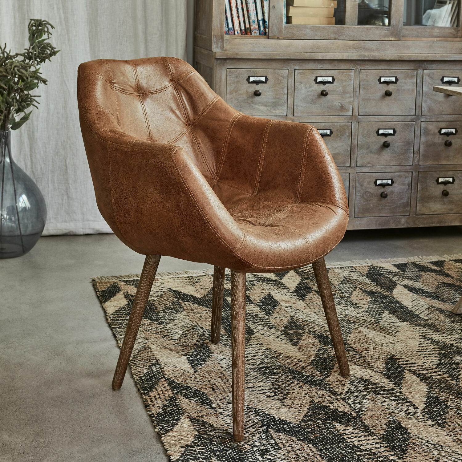 Chaise Montigny Fauteuil marron en similicuir avec pieds en bois sur tapis géométrique dans un salon