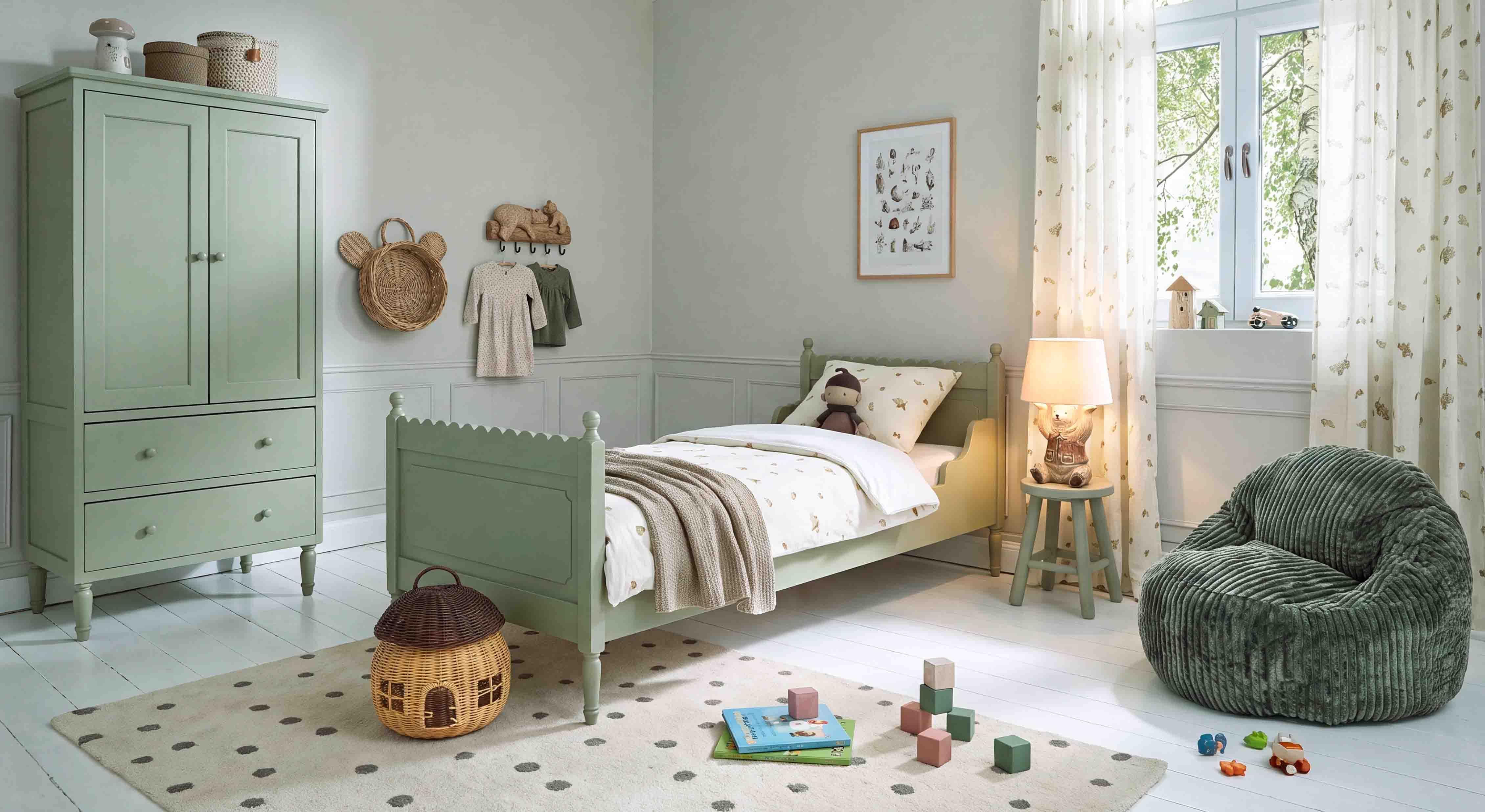 Armoire et lit en bois vert pastel dans une chambre d'enfant avec fauteuil doux et jouets