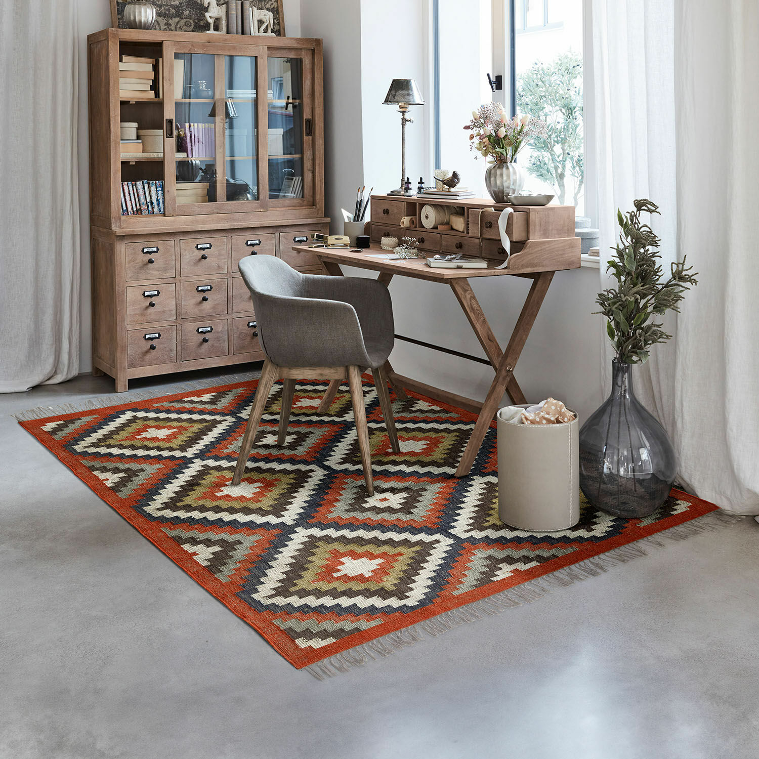 Tapis Dailies Tapis à motif géométrique aux tons chauds dans un bureau moderne avec bureau en bois et fauteuil gris