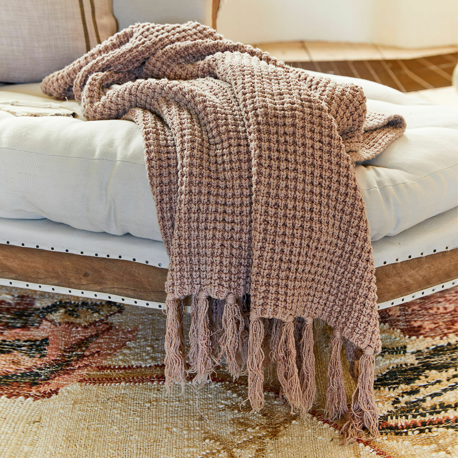 Plaid Kendall Plaid marron avec franges sur coussin blanc posé sur banc en bois, tissu doux pour salon